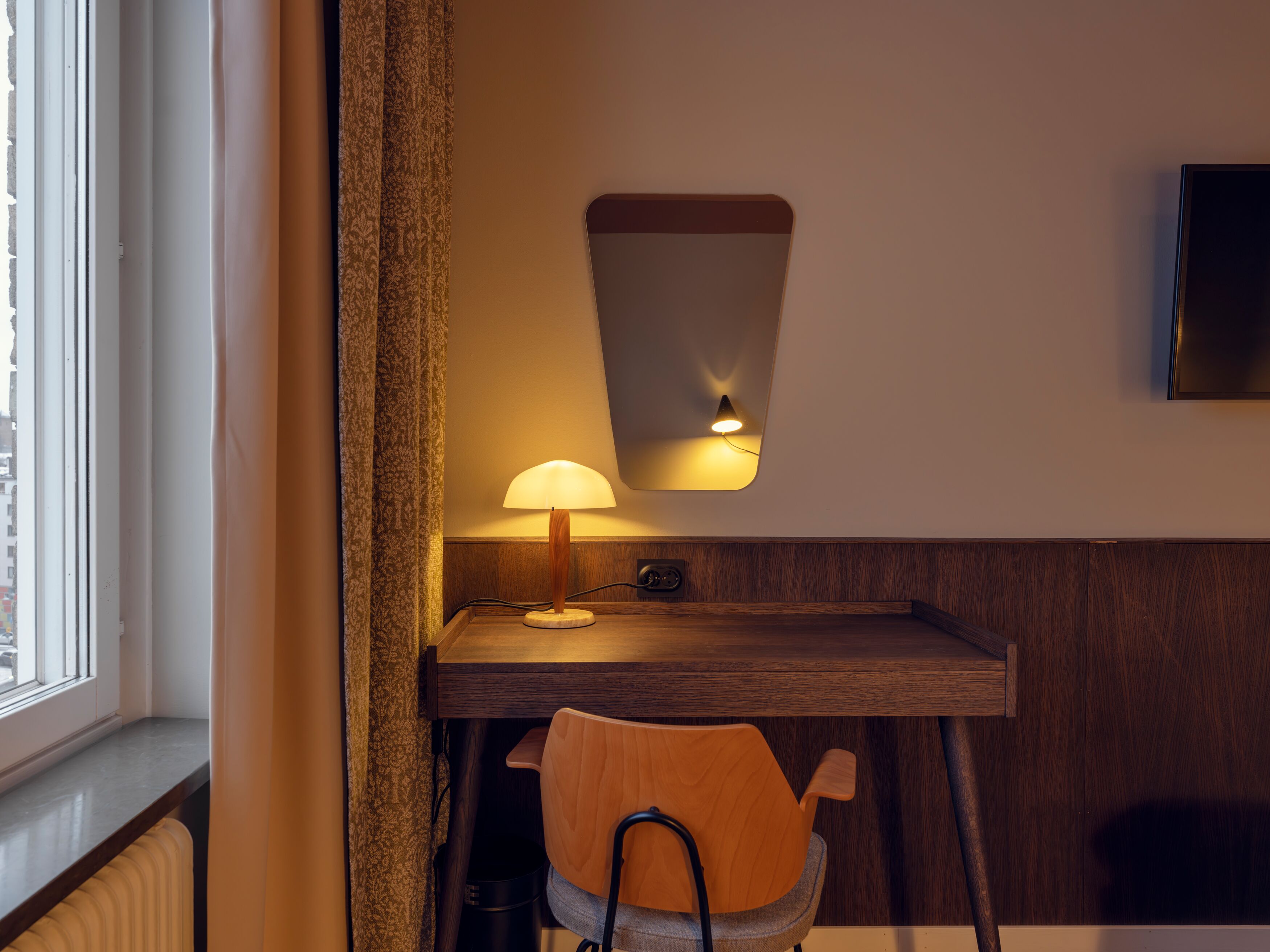 Ljust hotellrum med säng, fönster och blå textilier