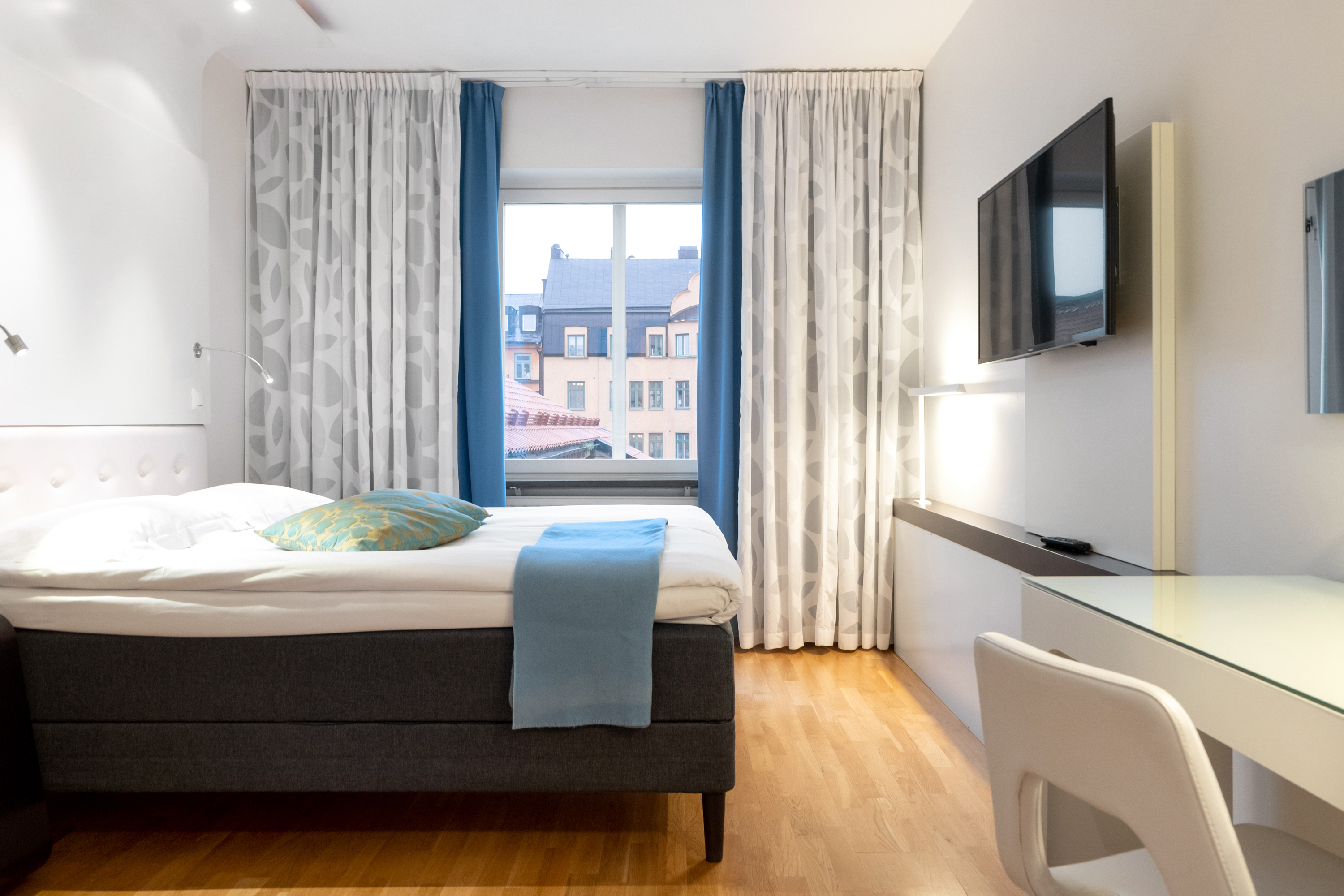 Ljust hotellrum med soffa, tv och fönster