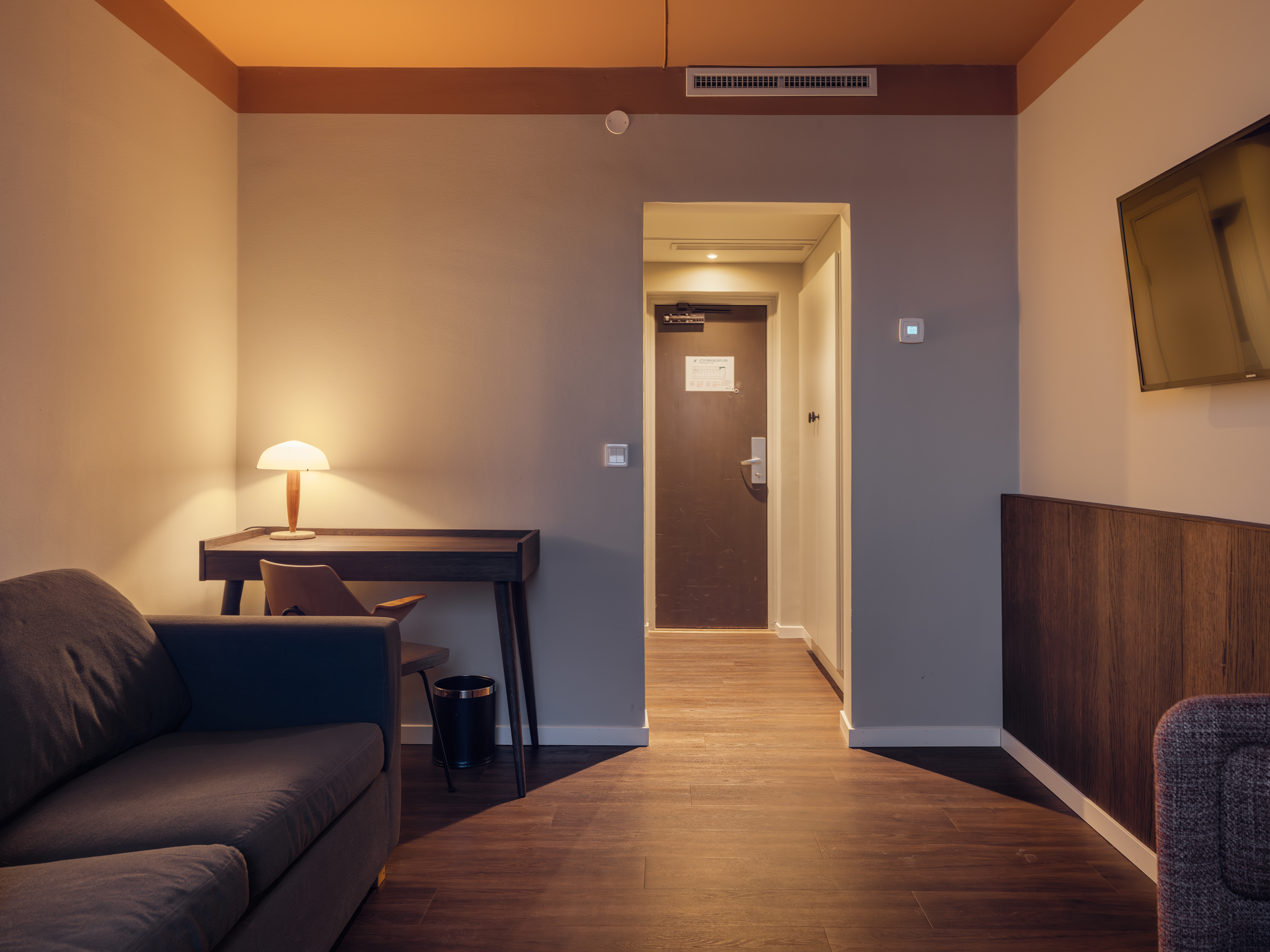 Ljust hotellrum med säng, fåtöljer och gardiner