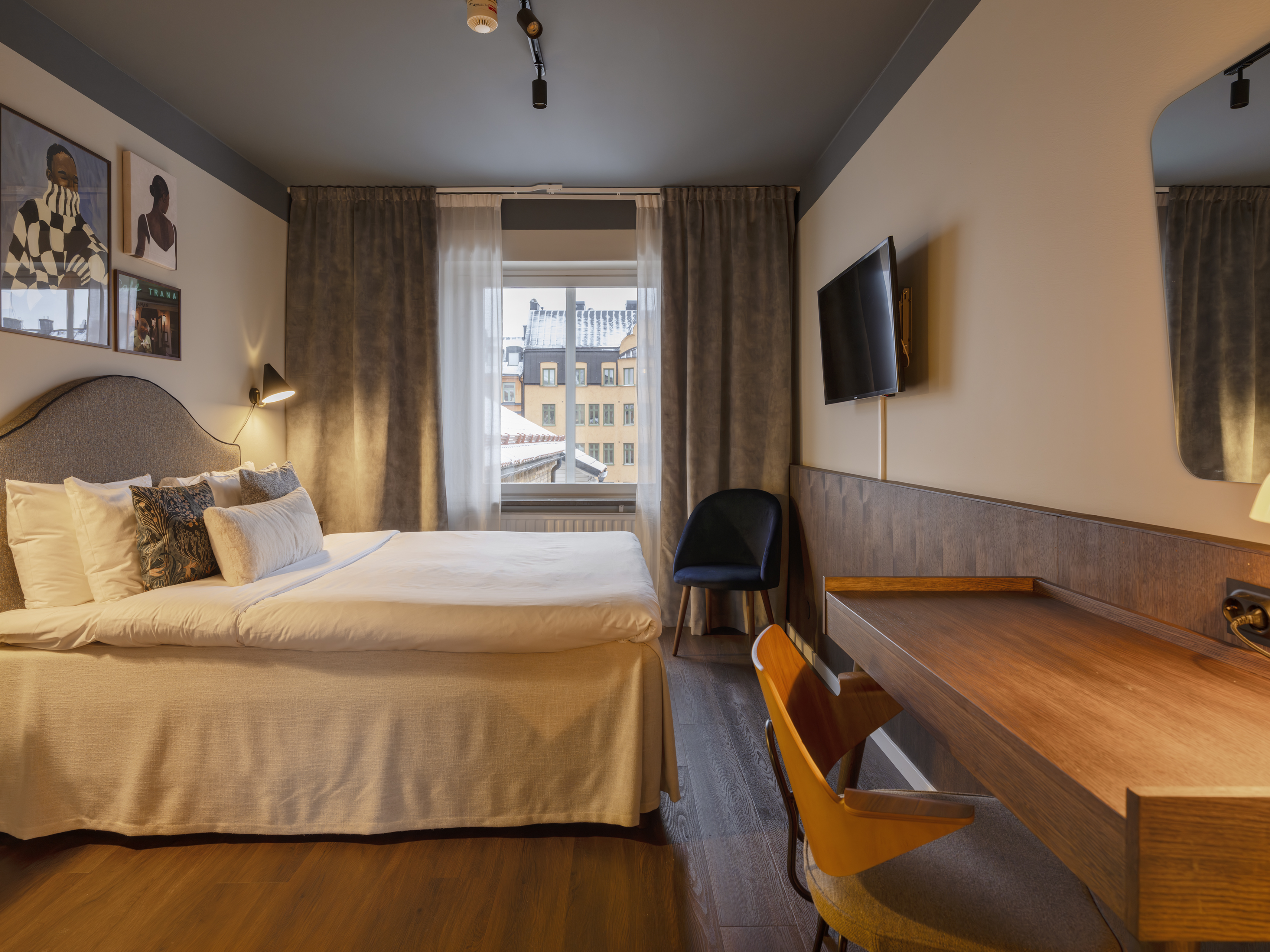 Ljust hotellrum med säng, blå textilier och fåtöljer