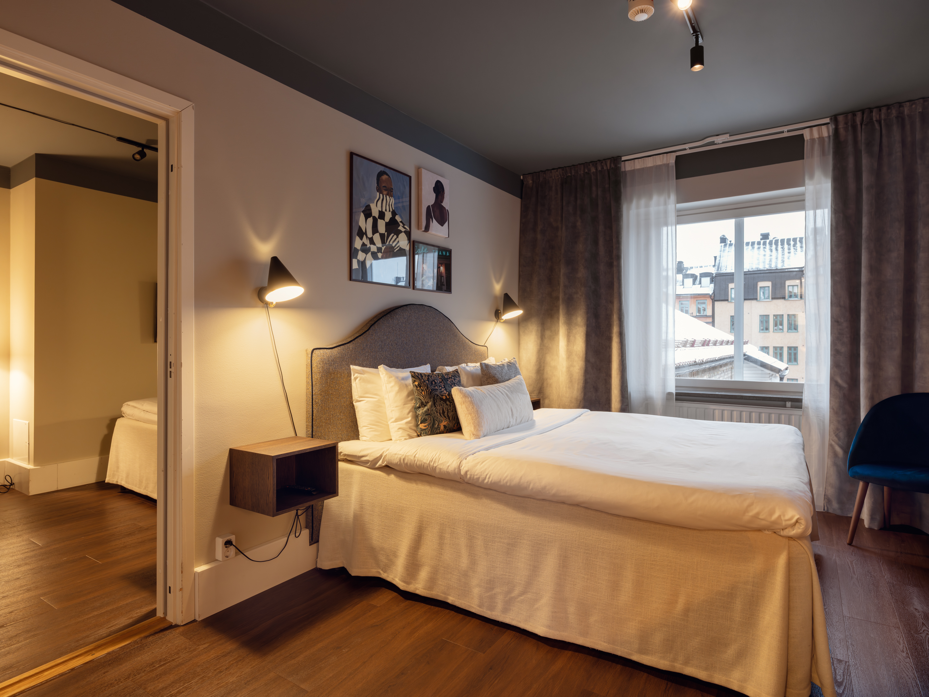 Ljust hotellrum med säng, gröna textilier och skrivbord