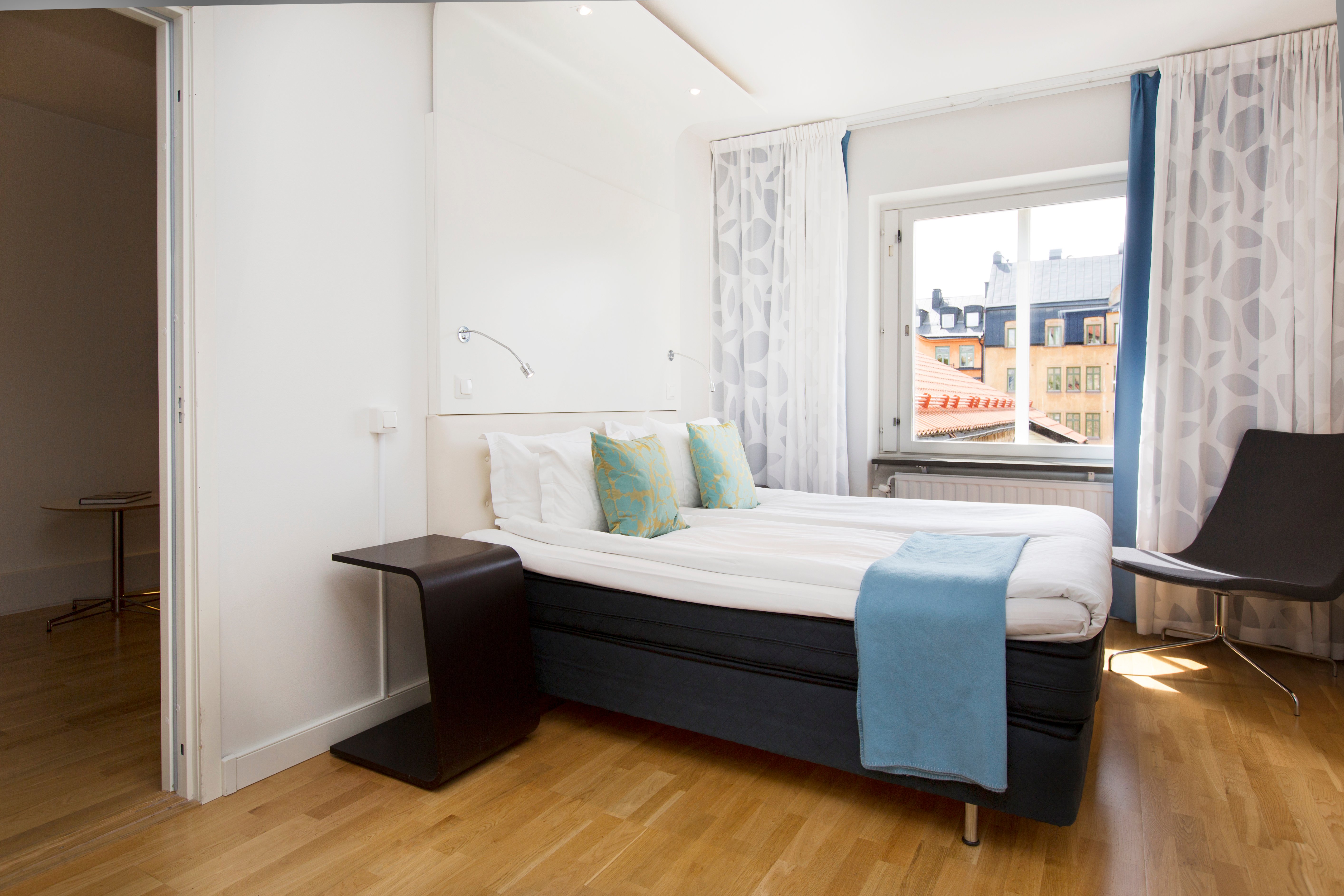 Bright hotel room with bed, blue textiles and armchairs