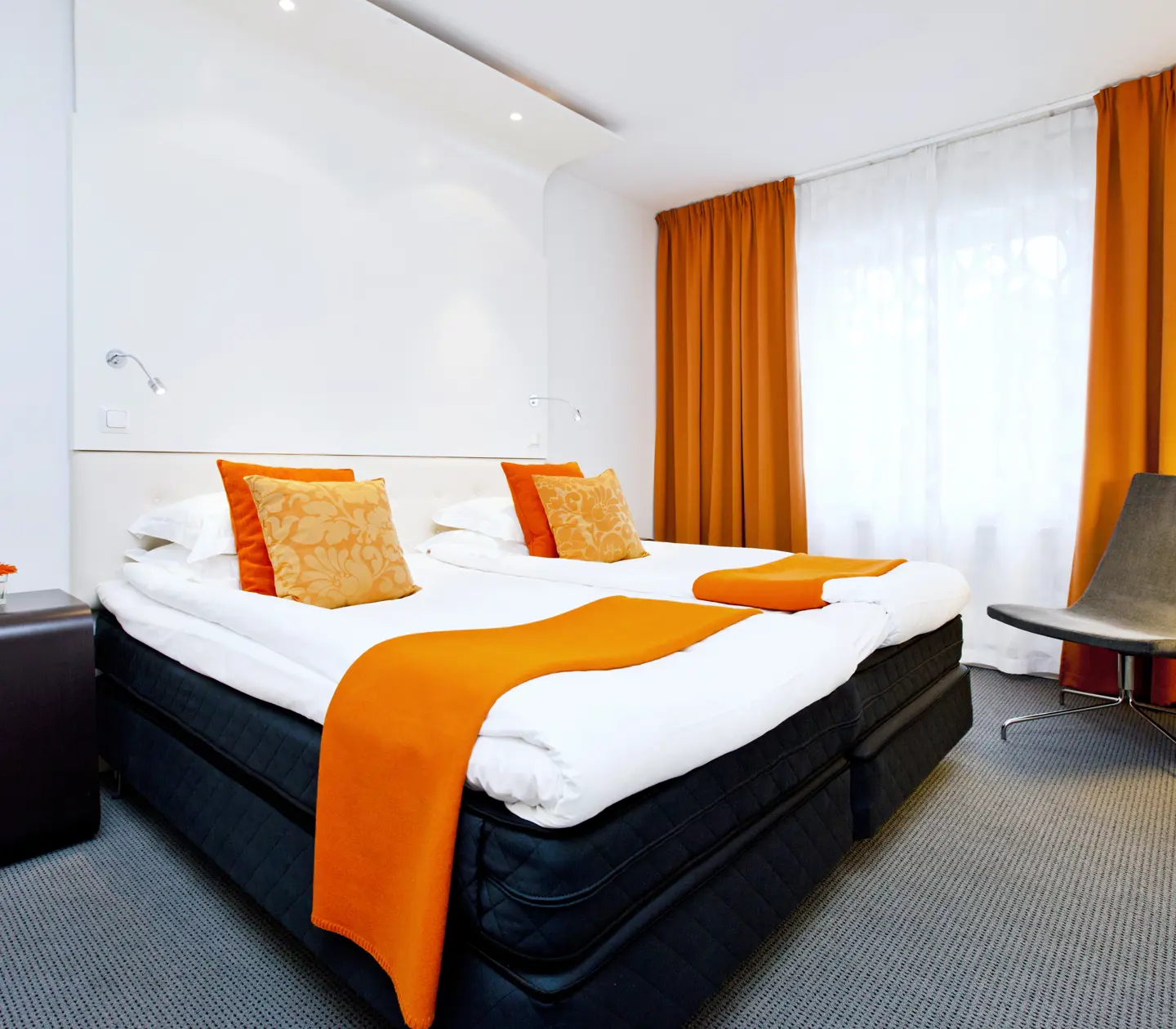 Bright suite with bed, orange textiles and curtains