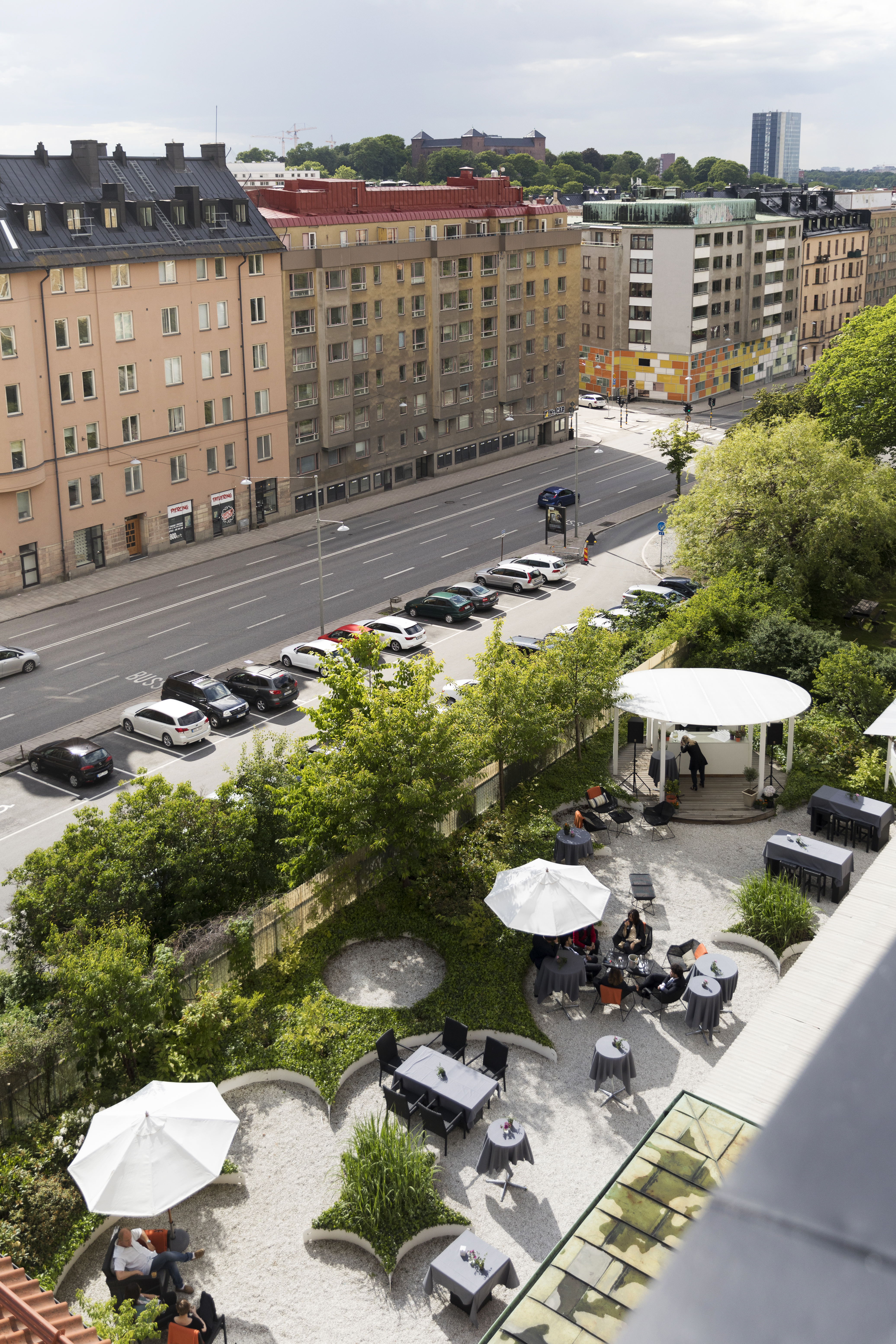 Uteservering med grönska, matgrupper och parasoll