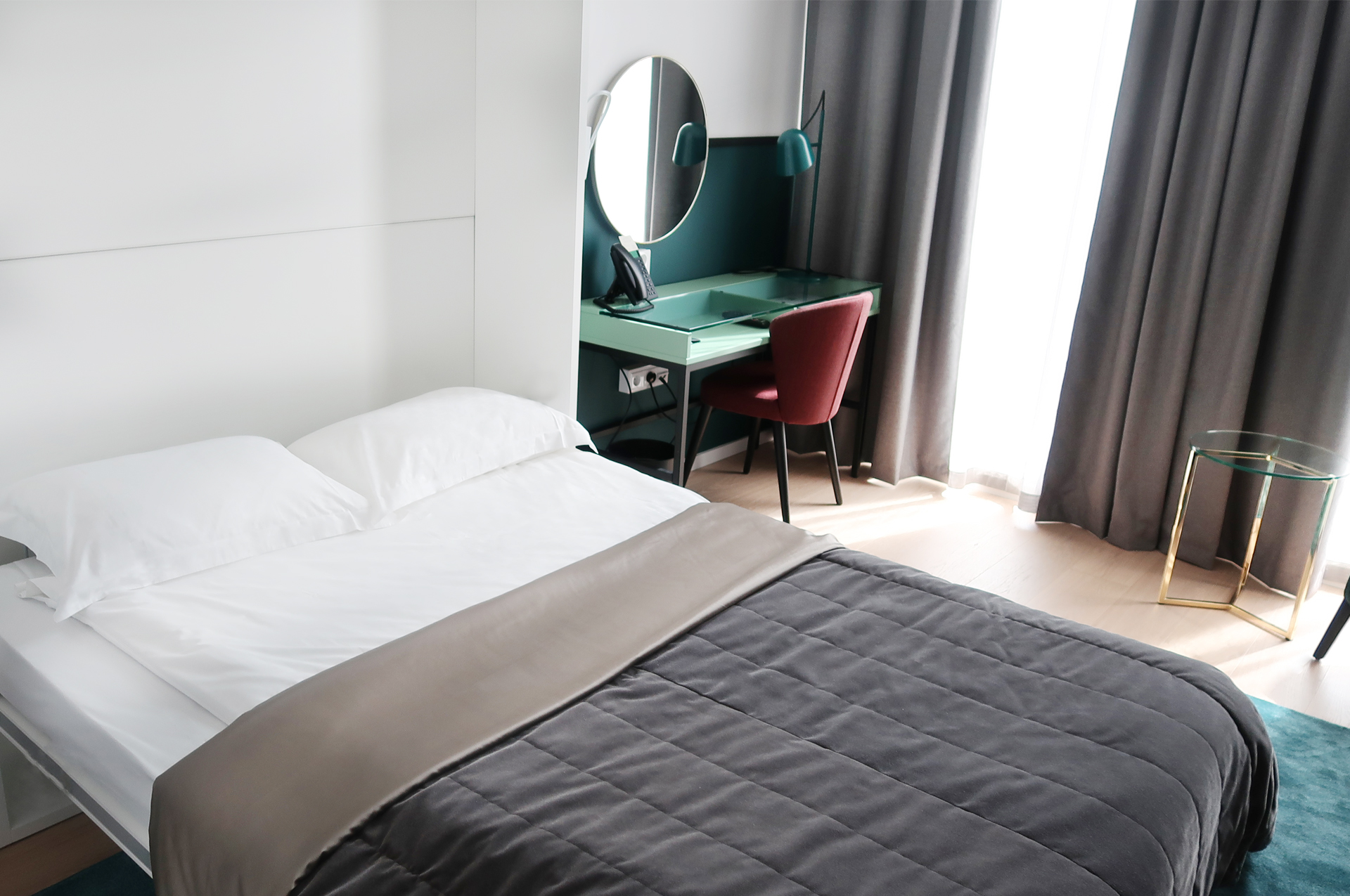 Bright hotel room with bed, desk and mirror