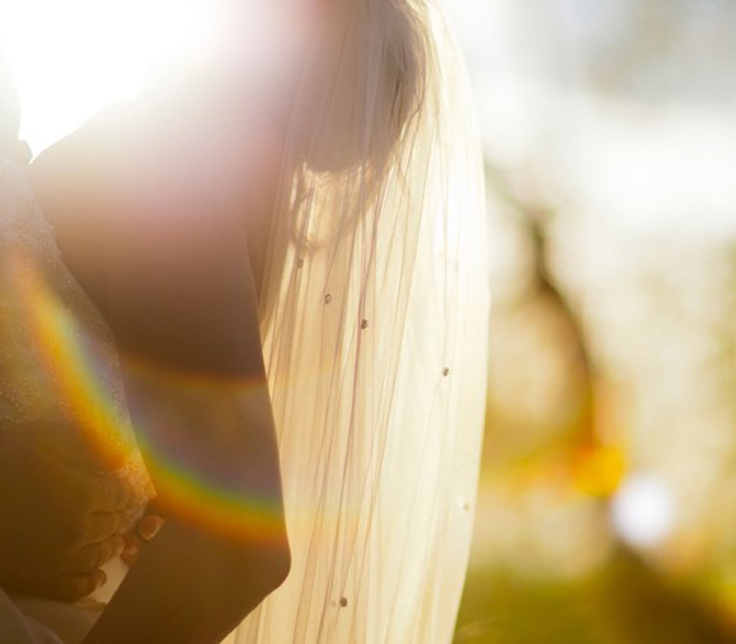 A man holds his woman in a wedding dress in sunlight.