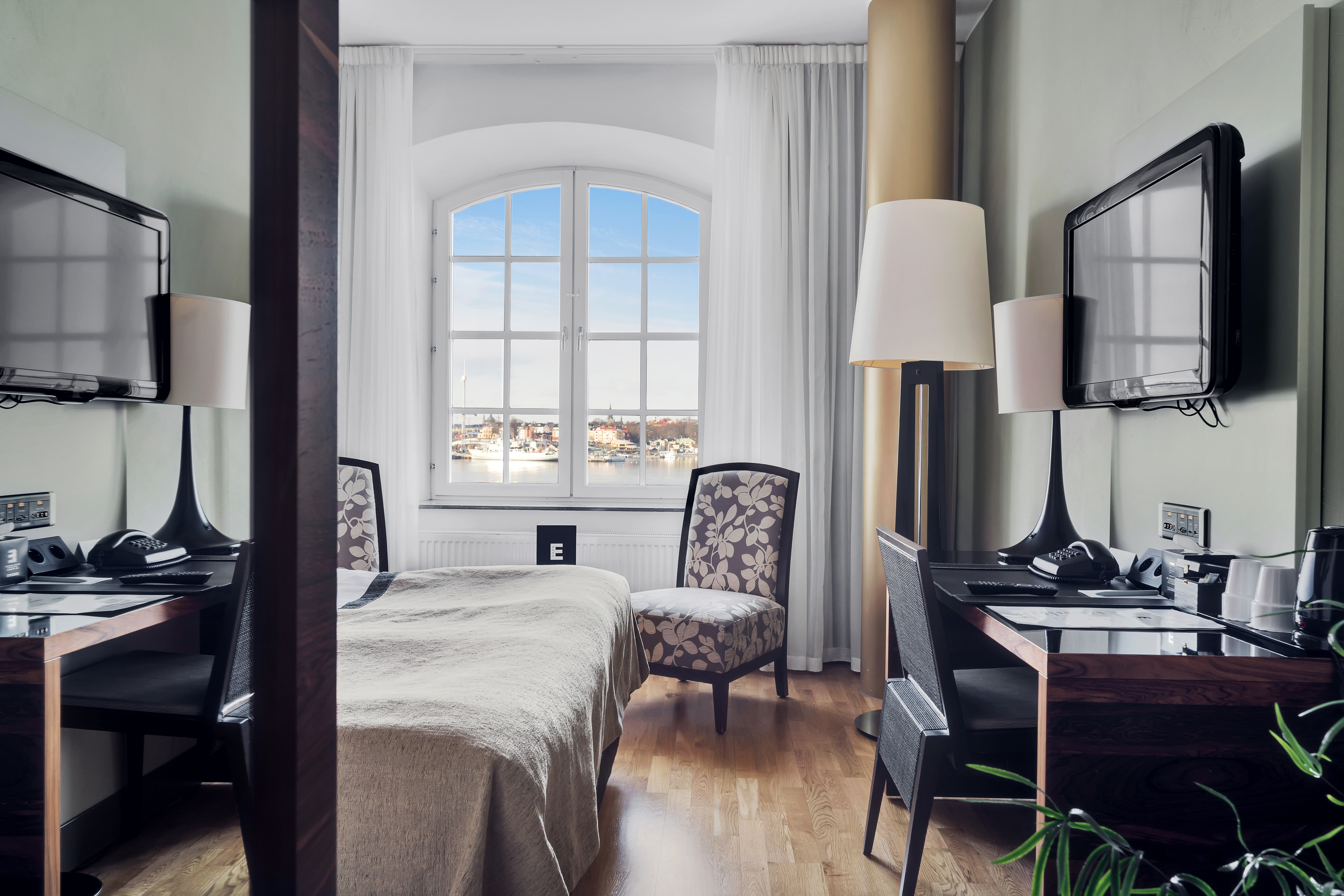 Bright hotel room with bed, desk and window with sea view