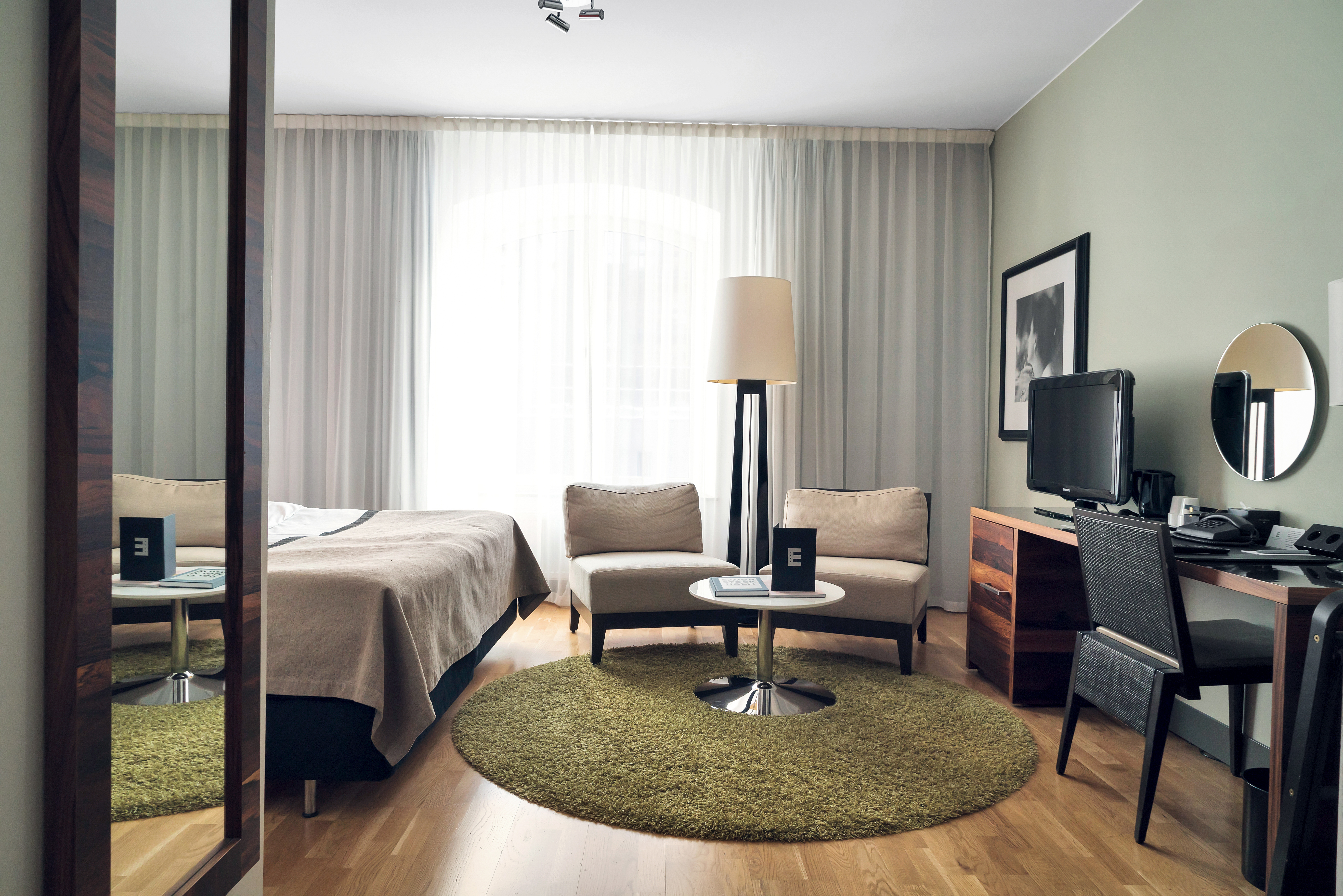 Bright hotel room with armchairs, desk and curtains