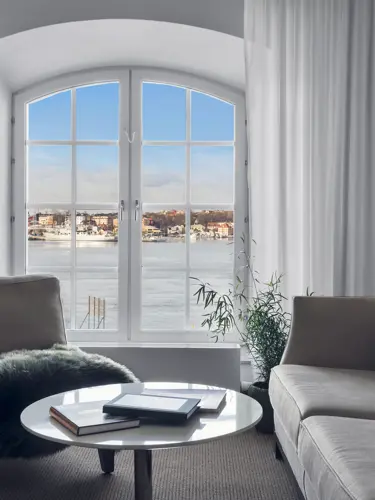 Hotellrum med soffa, golvlampa och fönster med havsutsikt