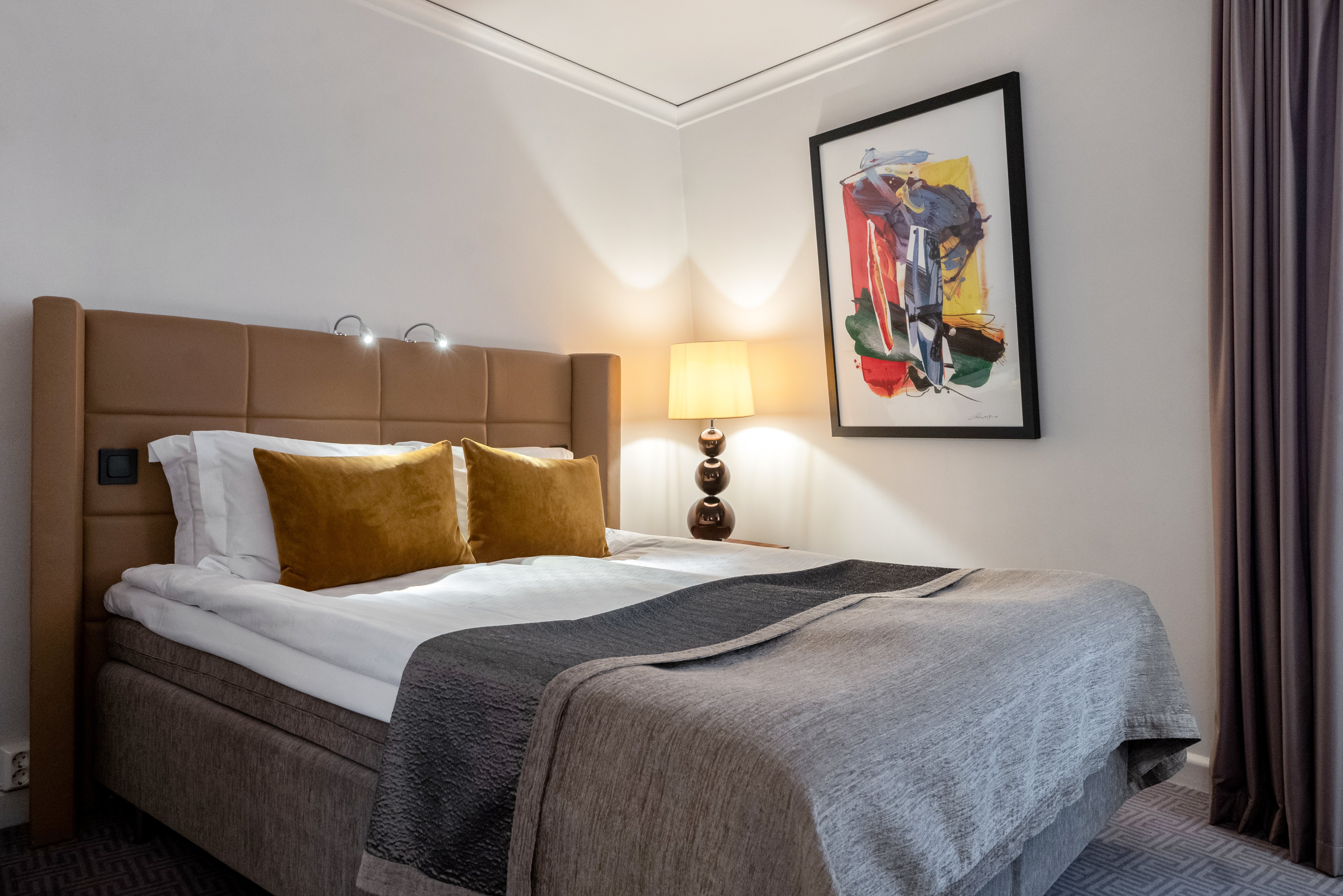 Cozy hotel room with double bed with yellow headboard, lamps and blackboard