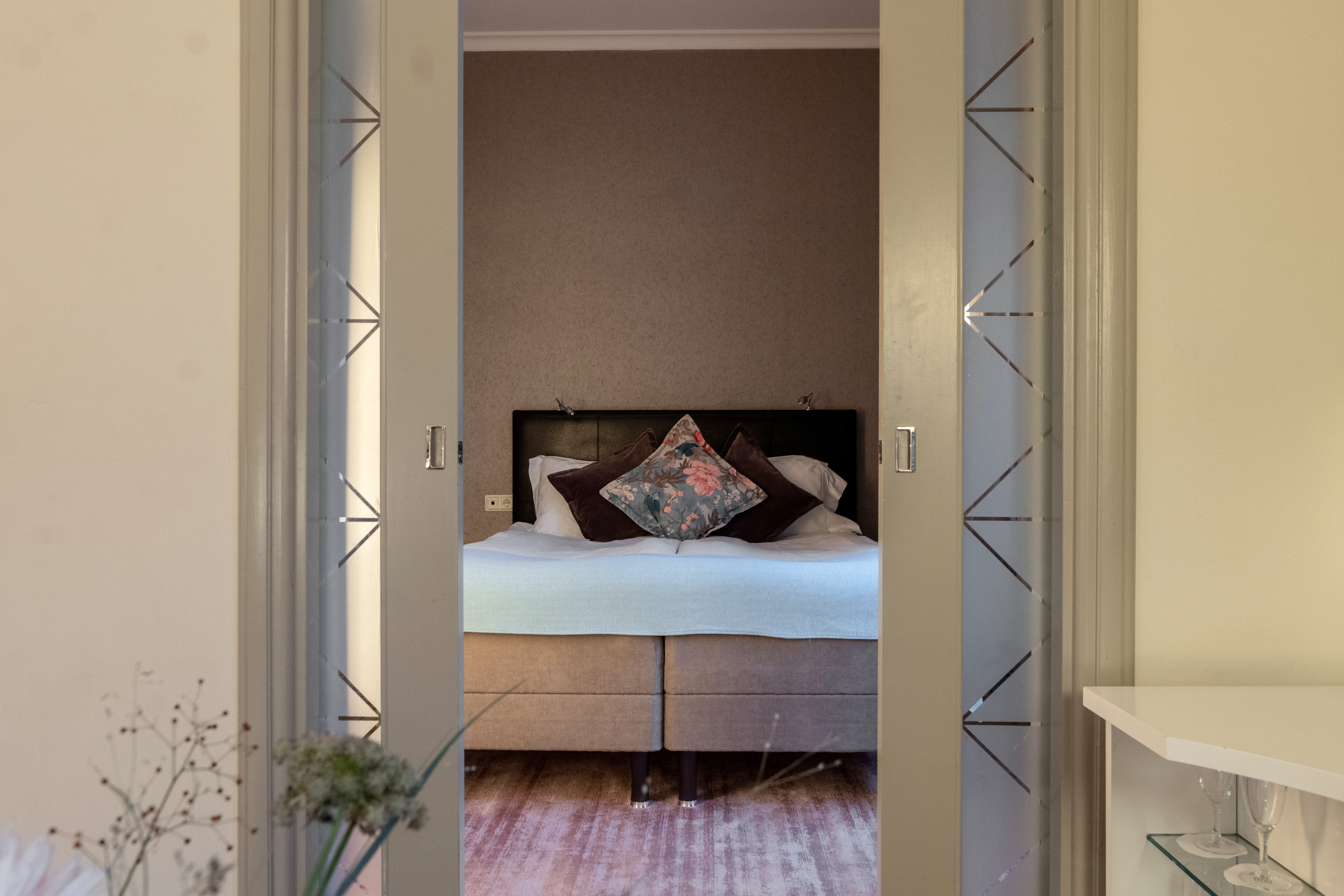 Cozy suite with opened glass doors to bedroom with double bed