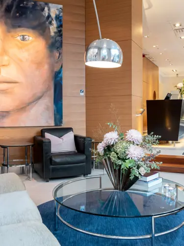 Hotellobby med loungemöbler, blombukett och tavla med ansikte