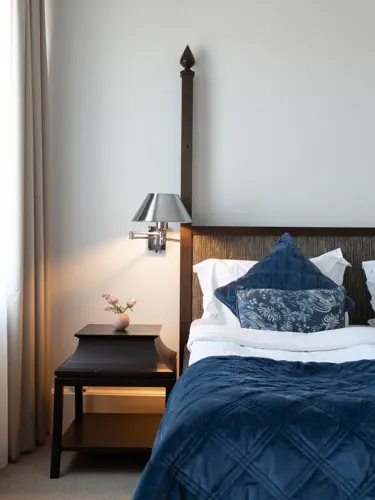 Hotellrum med dubbelsäng, sängbord och fönster