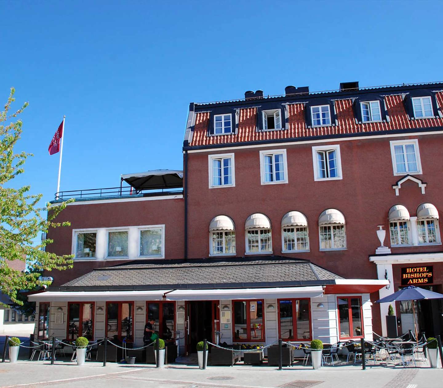 The red facade of the Hotel Bishops Arms with outdoor seating outside