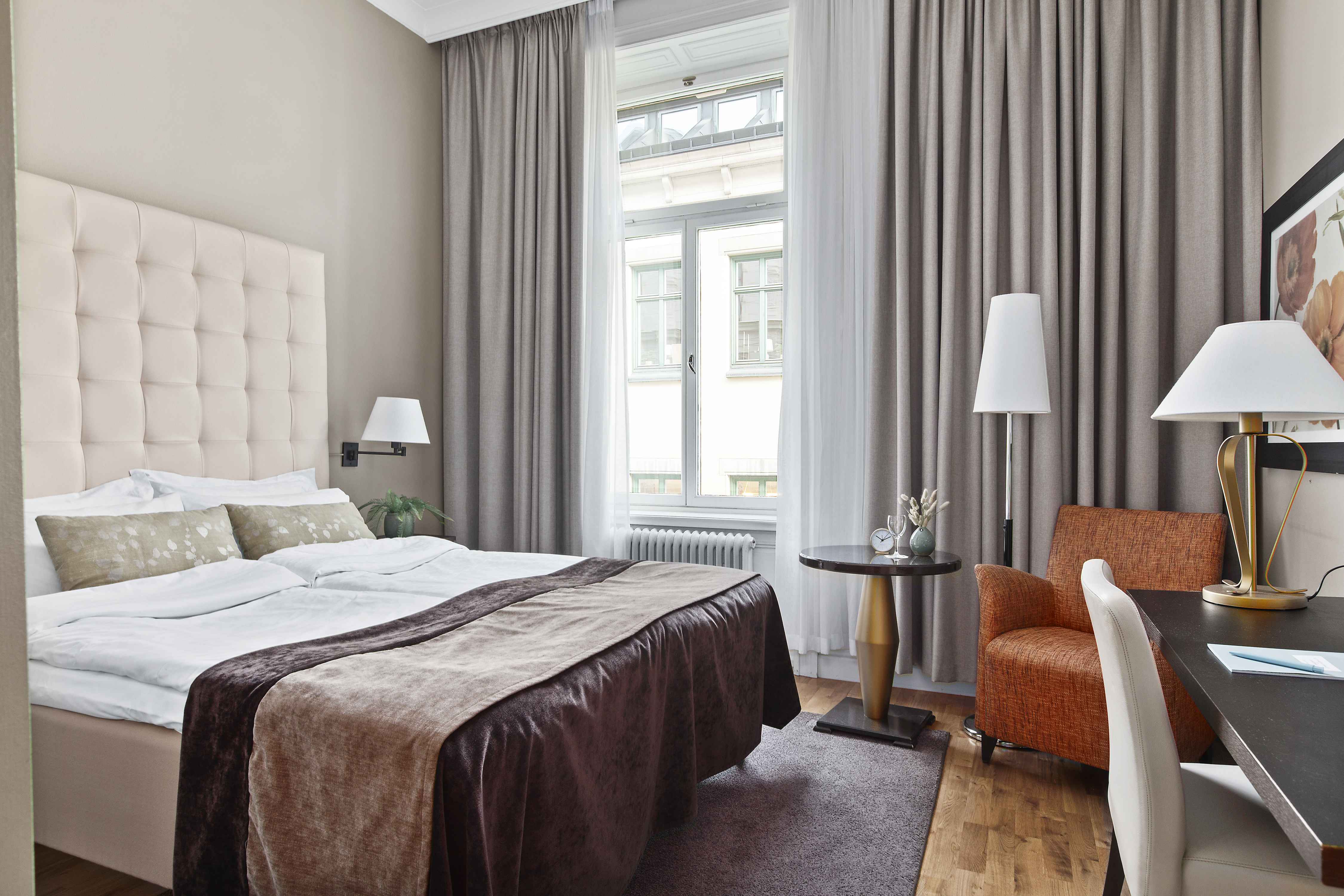 Bright hotel room with bed, white headboard and armchair