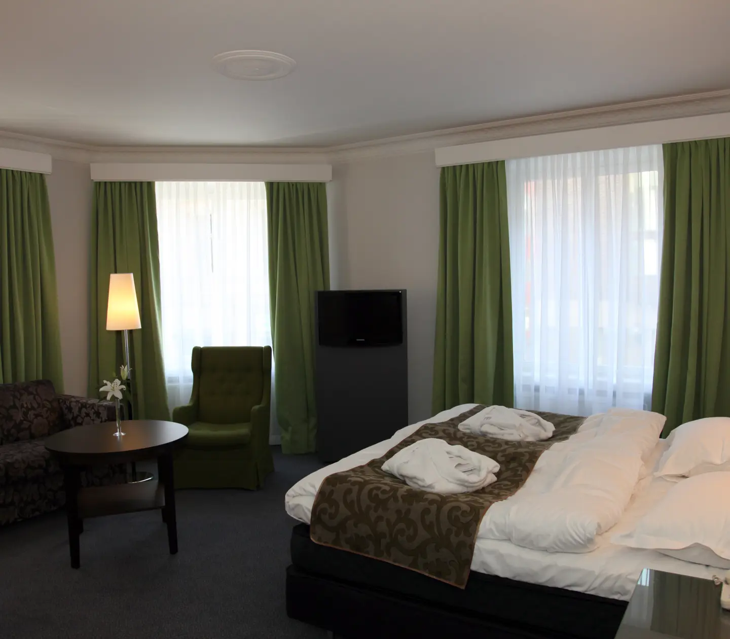 Ljust hotellrum med säng, soffa och stora fönster
