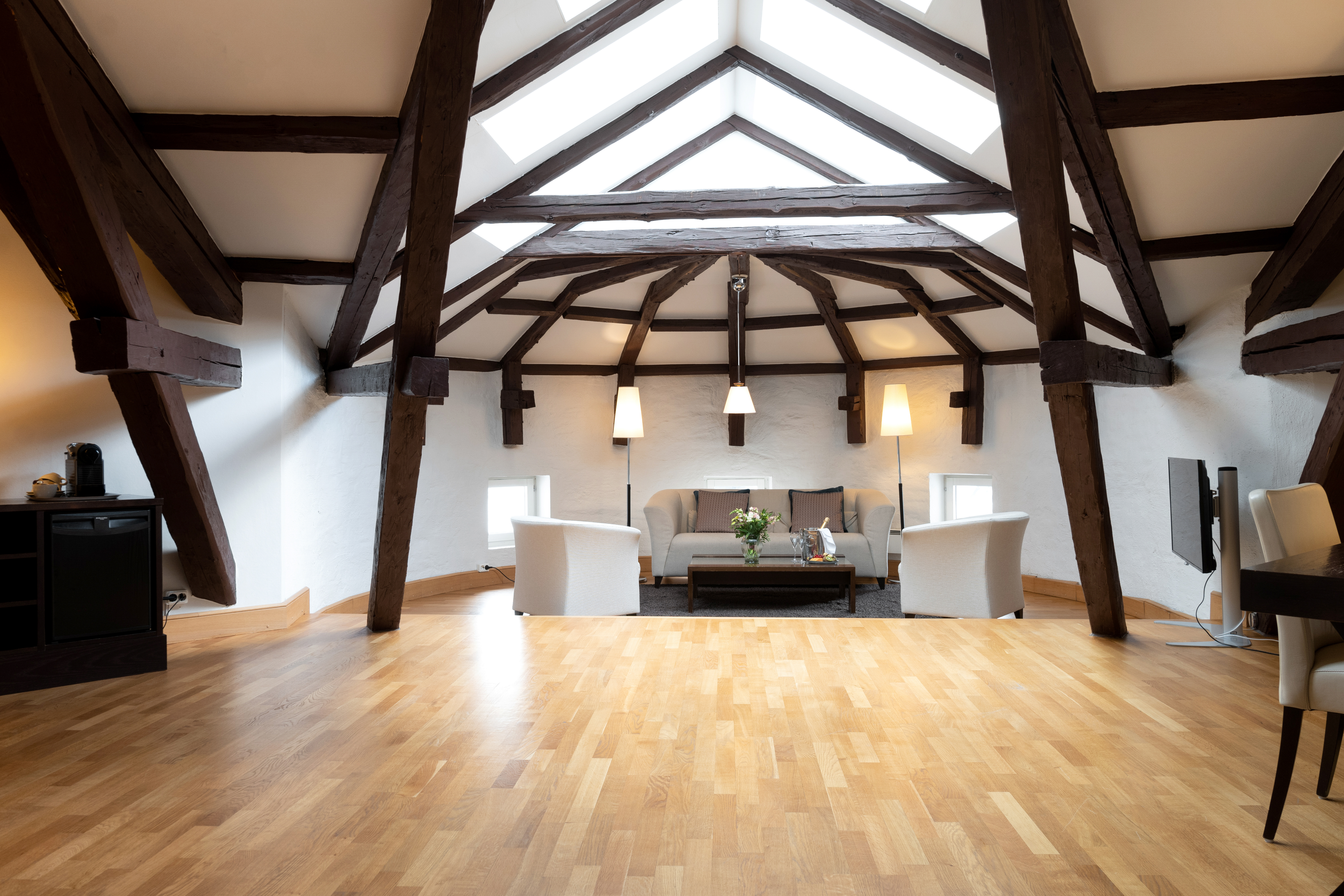 Bright suite with wooden beams from the ceiling, sofa group and skylight