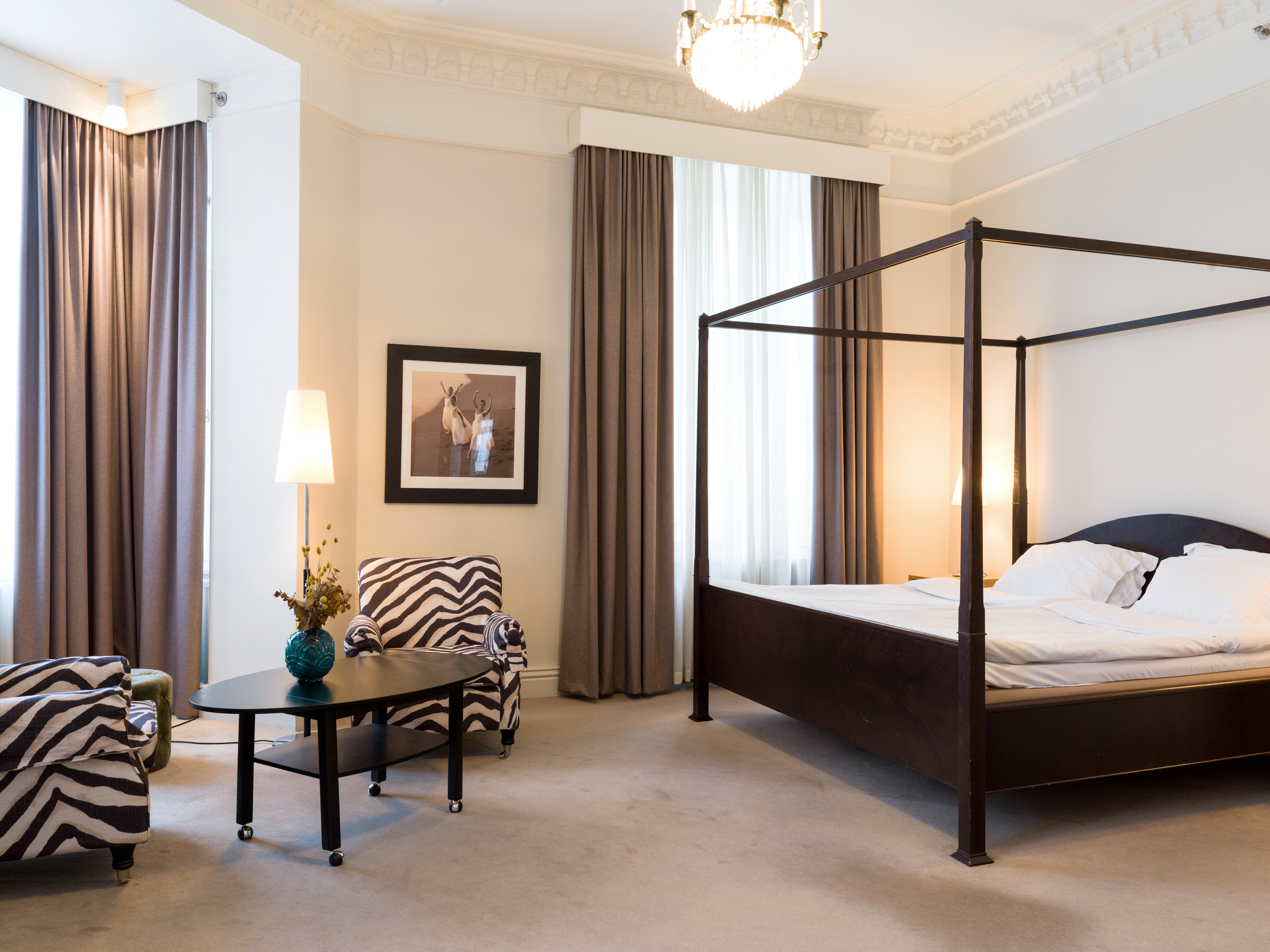 Bright suite with bed, wooden frame and zebra-patterned armchairs