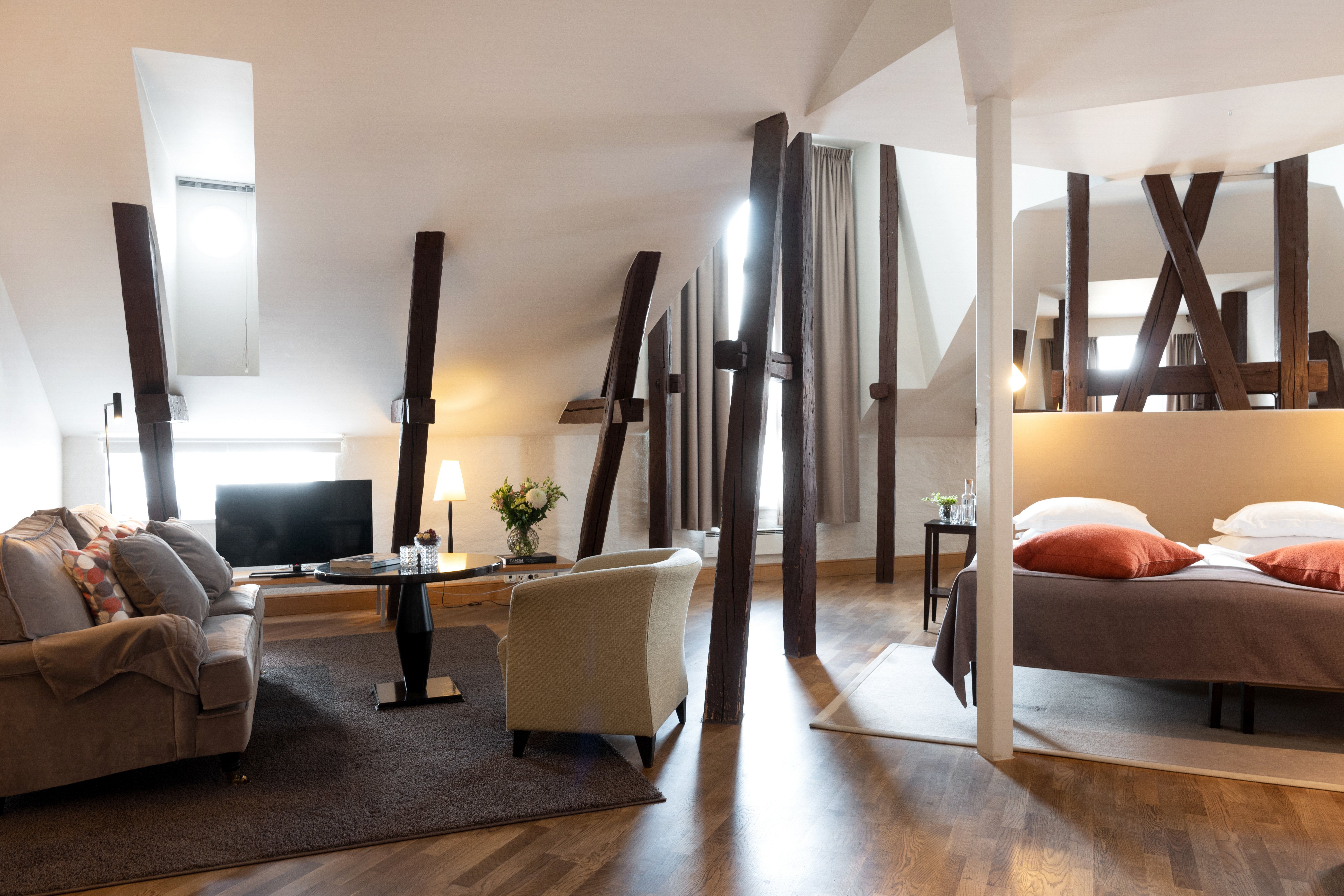 Hotel suite with bed, sofa group and wooden beams from the ceiling