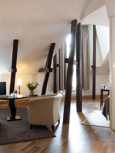 Hotel suite with wooden beams, bed and sofas