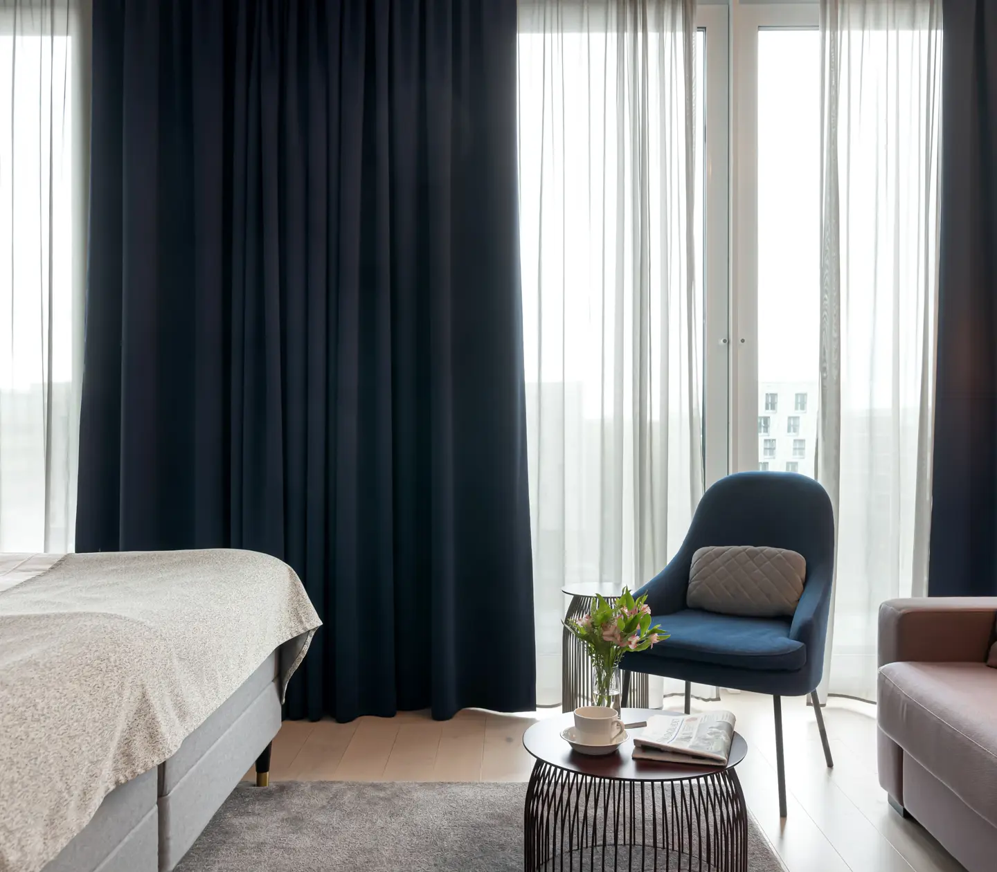 Mysigt hotellrum med soffgrupp, mörka gardiner och stort fönster