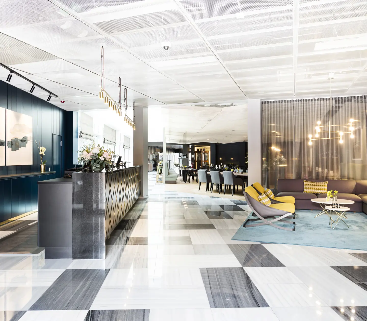 Hotellobby med receptionsdisk, loungemöbler och restaurang i bakgrunden
