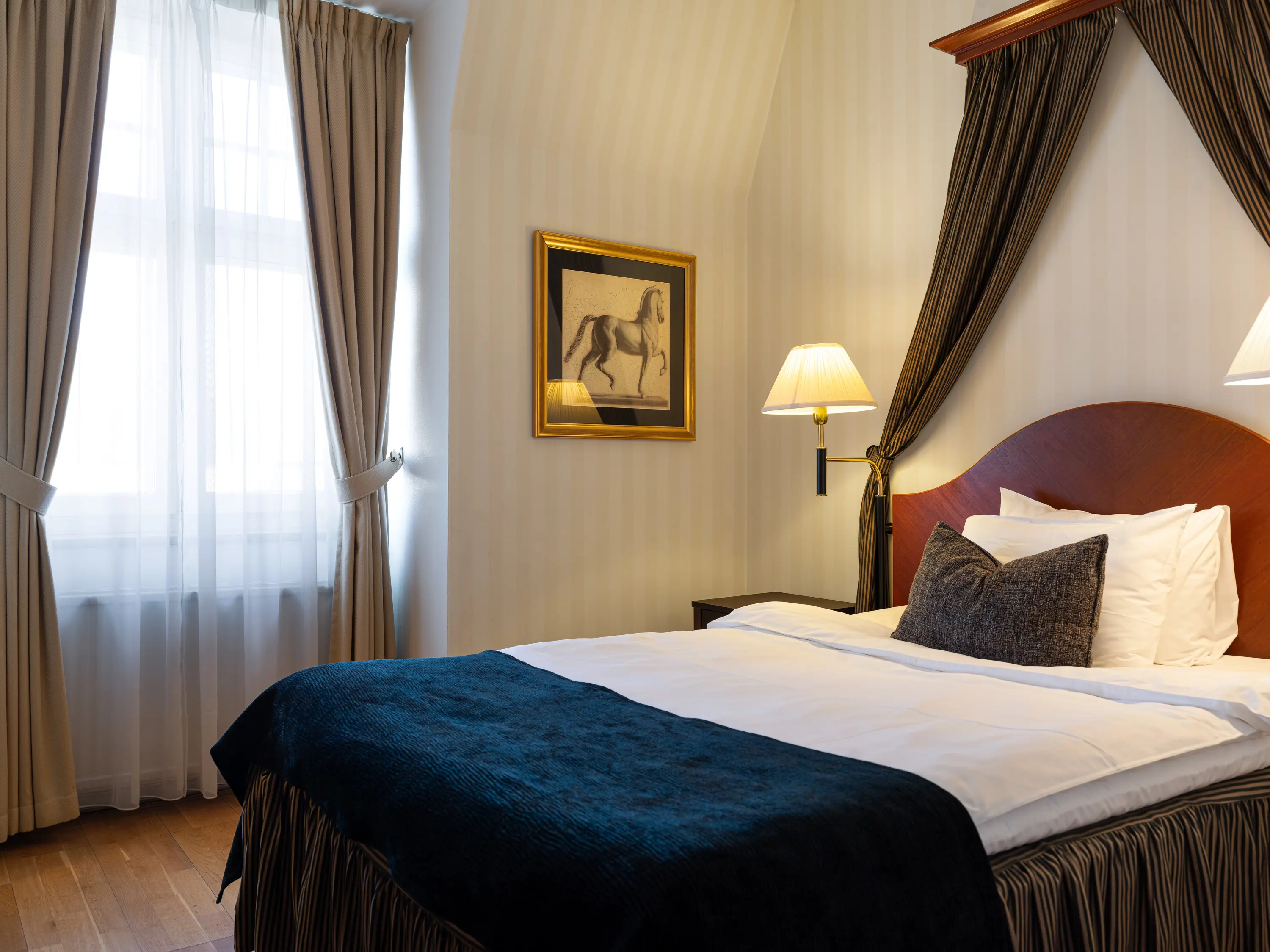Elegant hotellrum med dubbelsäng, vit sängkläder och blå överkast. 