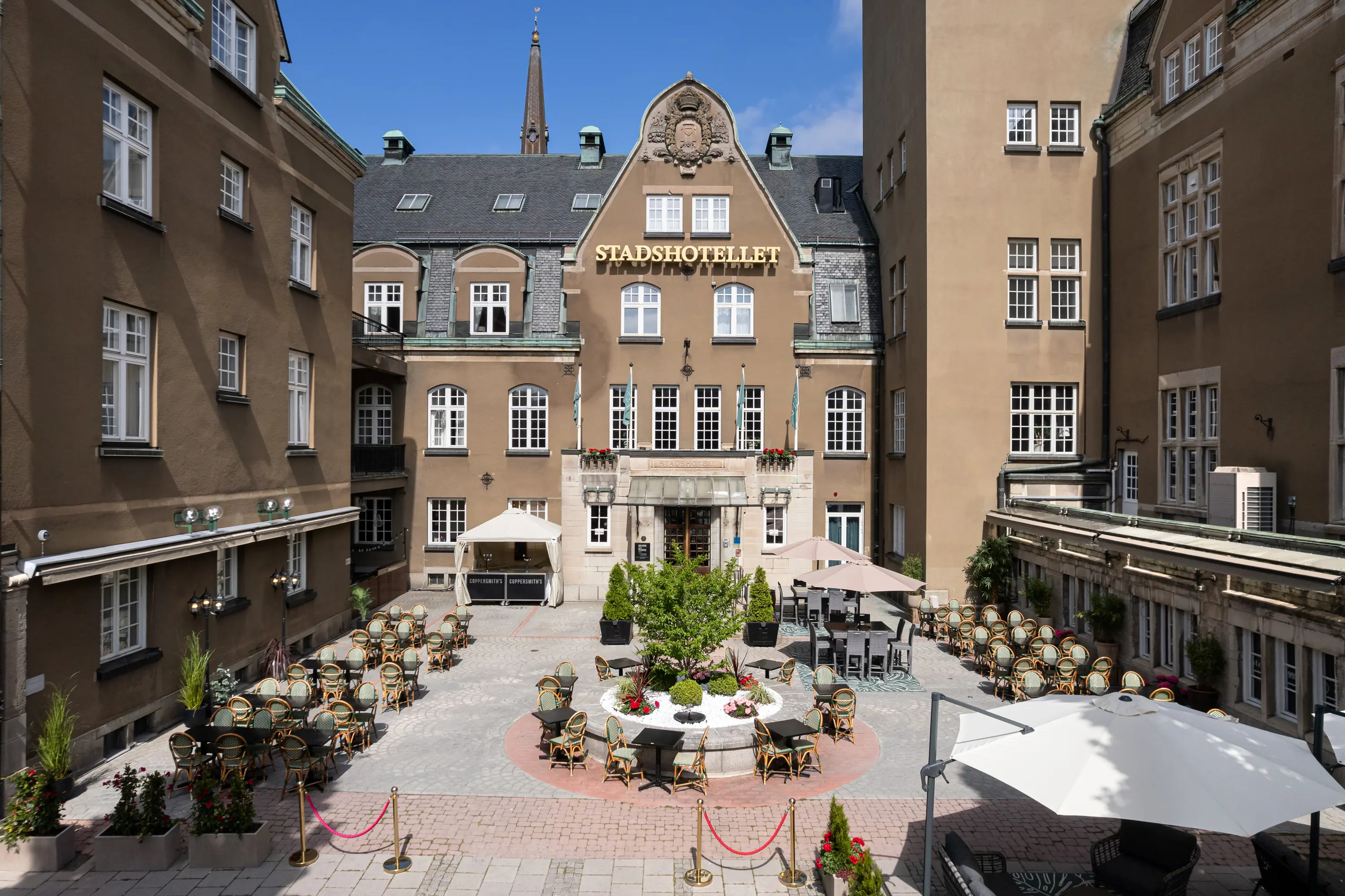 Öppen dörr till konferensrum med rund bord, fönster och kristallkrona