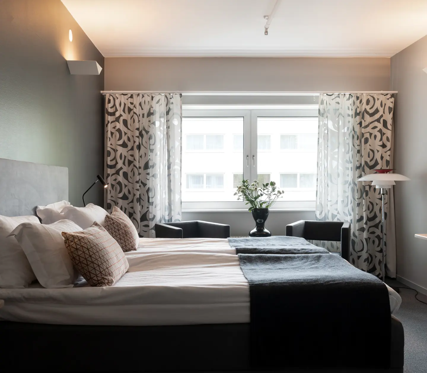 Ljust hotellrum med dubbelsäng, skrivbord och fönster