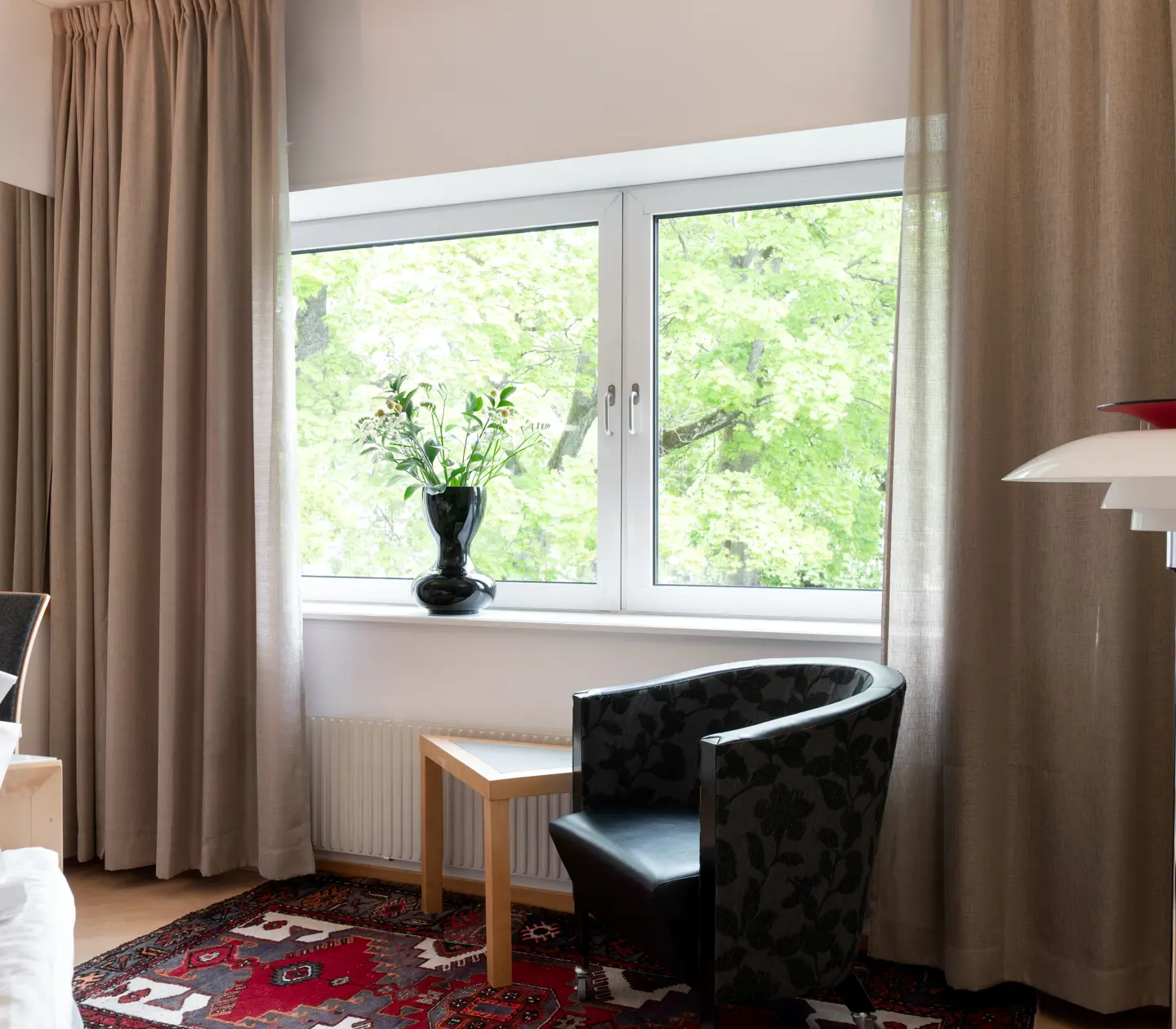 Hotellrum med golvlampa, fåtölj och fönster