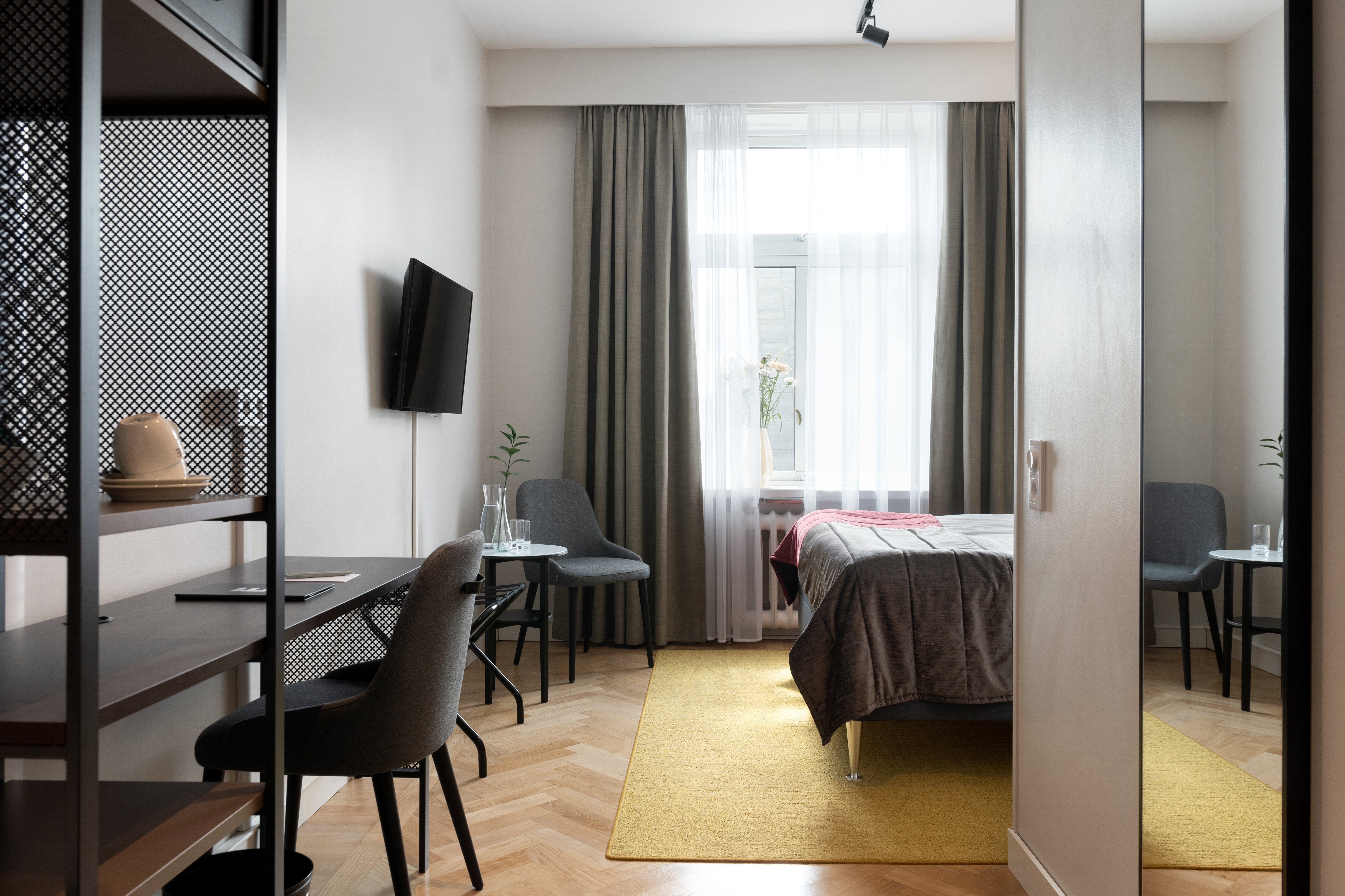 Hotel room with desk, armchair, TV and window