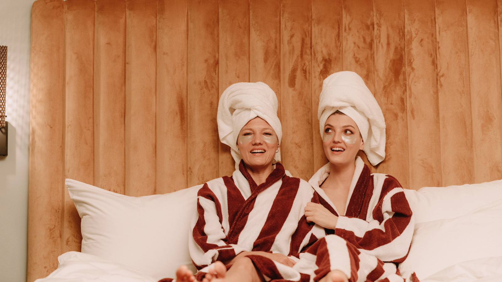Two women in bathrobes in a hotel bed