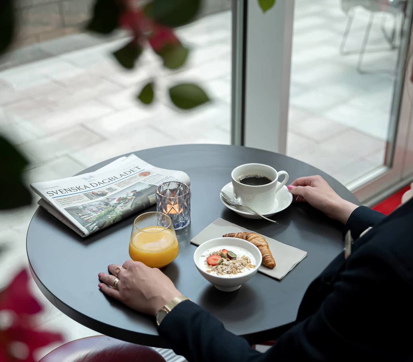 En person tar en fika på ett bord vid fönstret