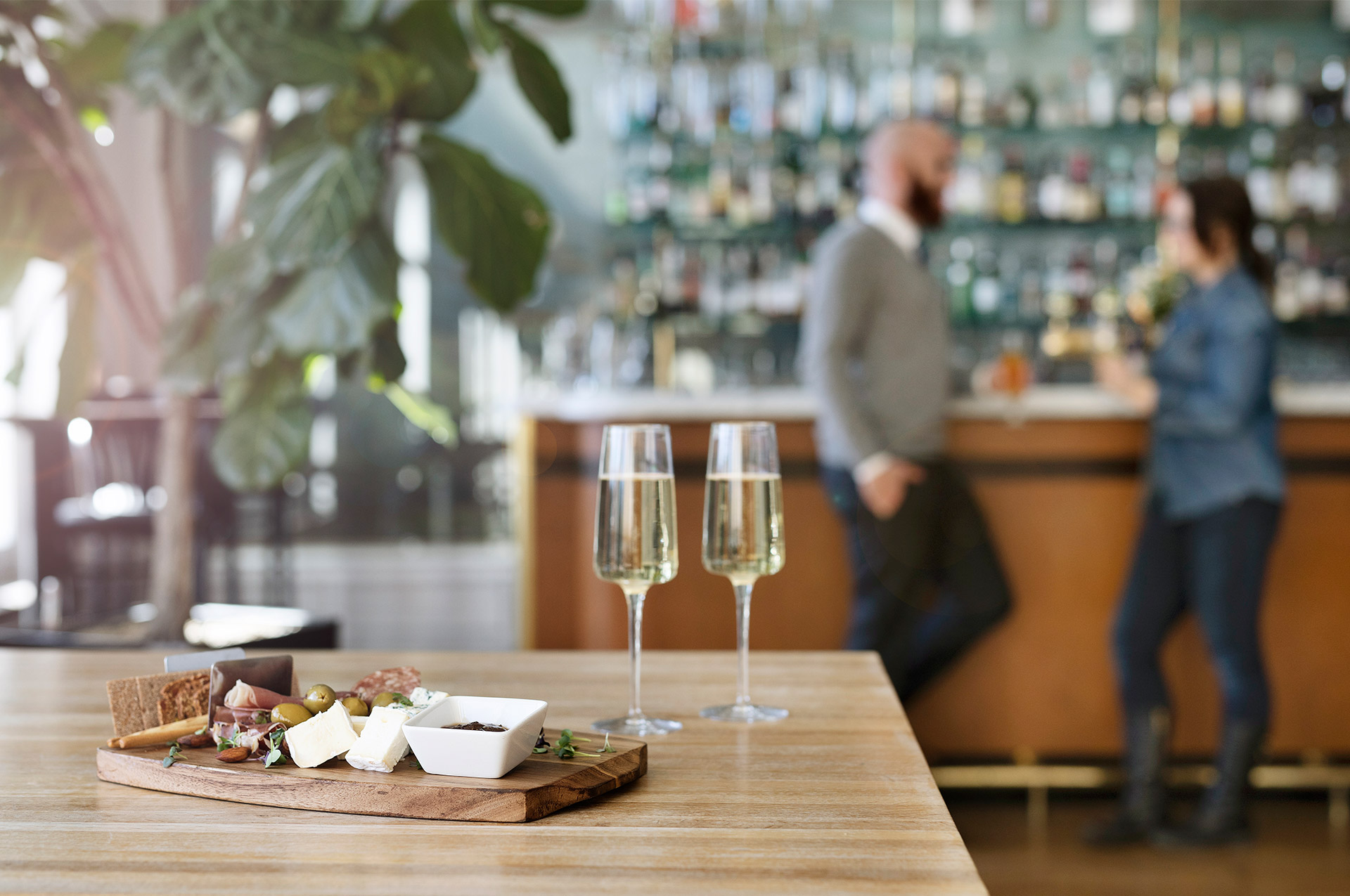 Charkbricka med Champagneglas på bord och två personer i bakgrunden