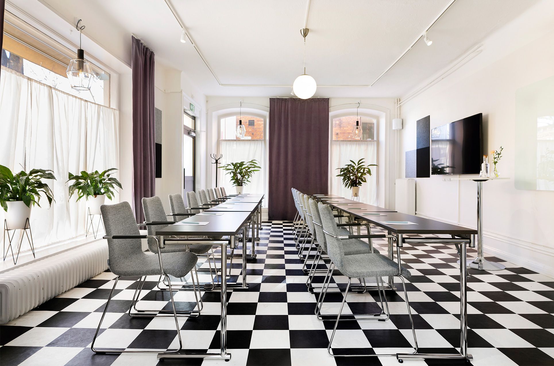 Konferensrum med schackrutigt golv, stolar och stora fönster