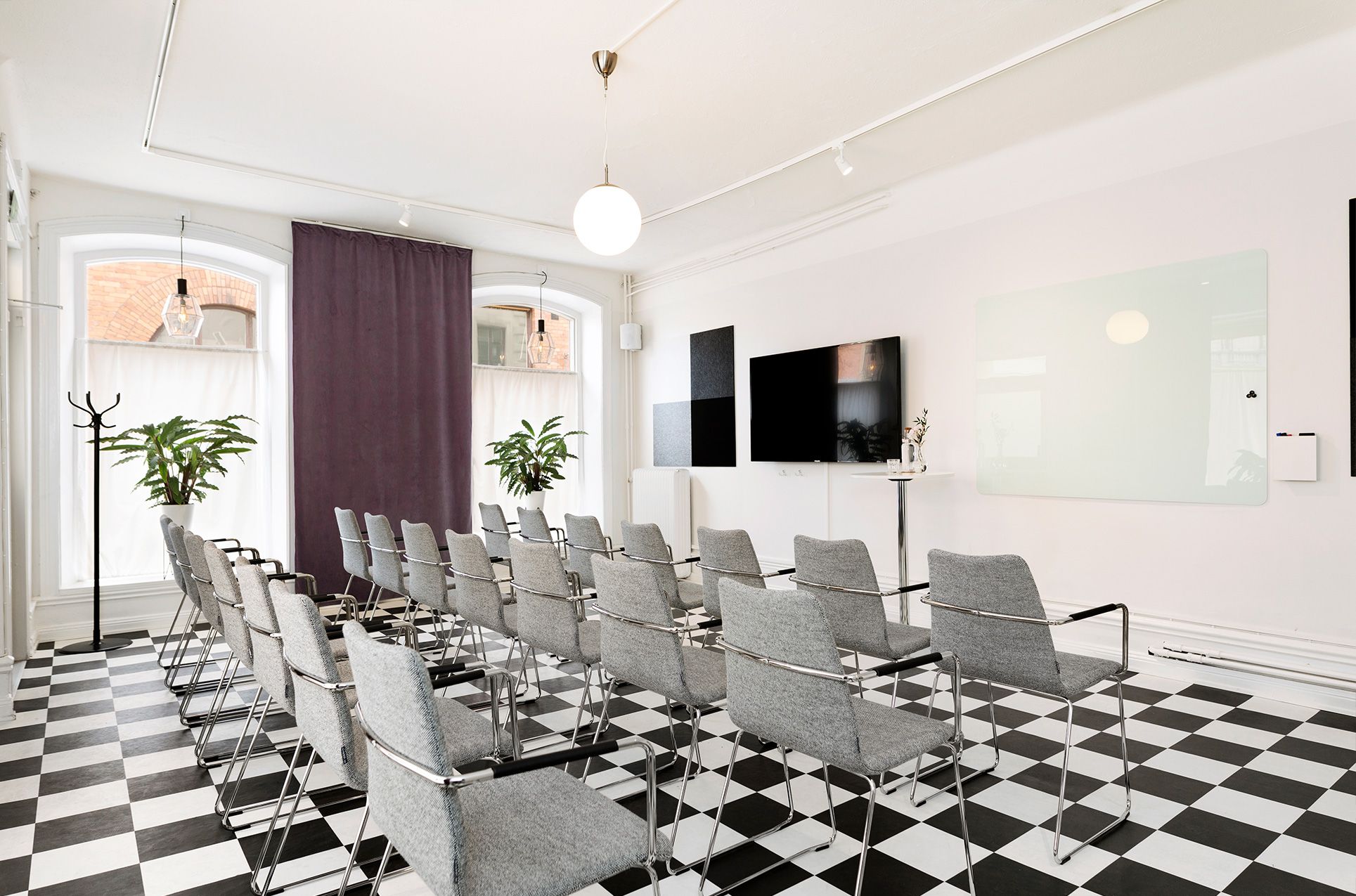 Konferensrum med schackrutigt golv, stolar och stora fönster