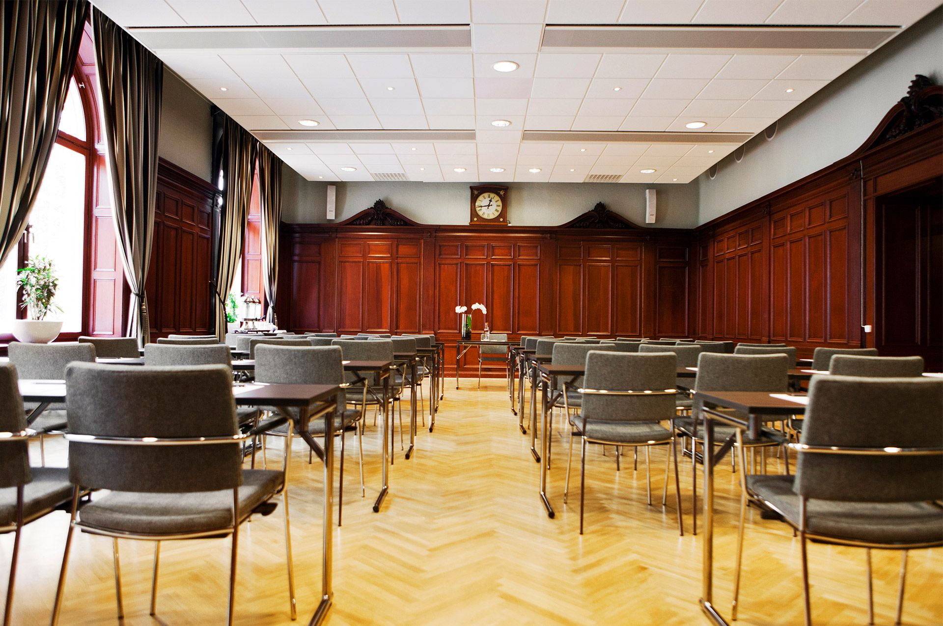 Röd konferenssal med många stolar, bord och fönster