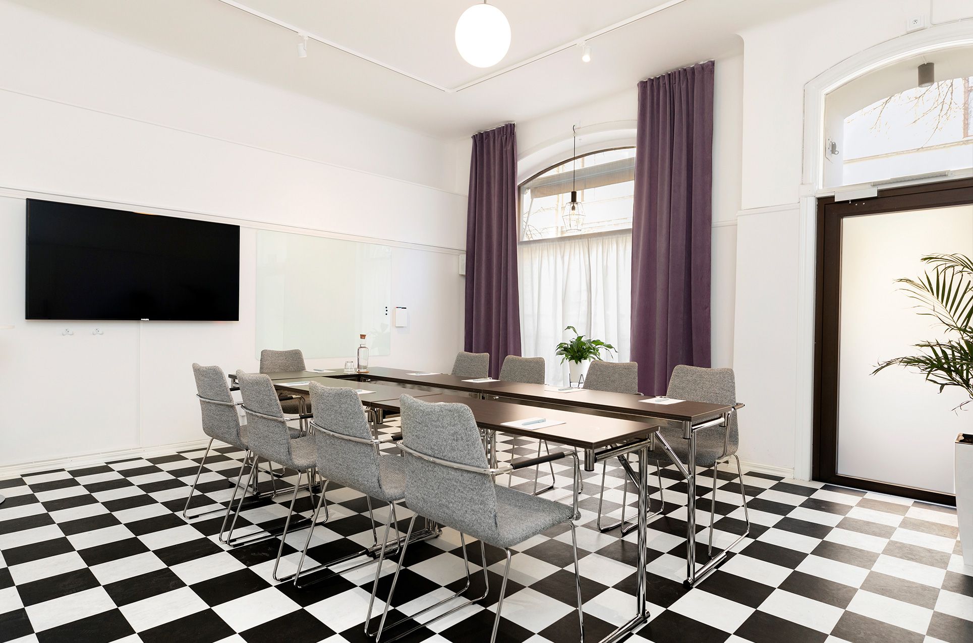 Konferensrum med schackrutigt golv, bord och stolar
