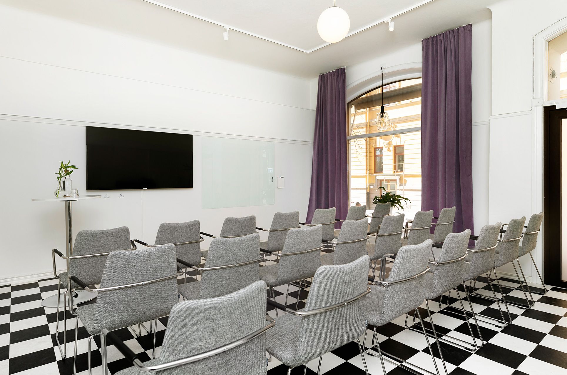 Konferensrum med schackrutigt golv, stolar och stort fönster