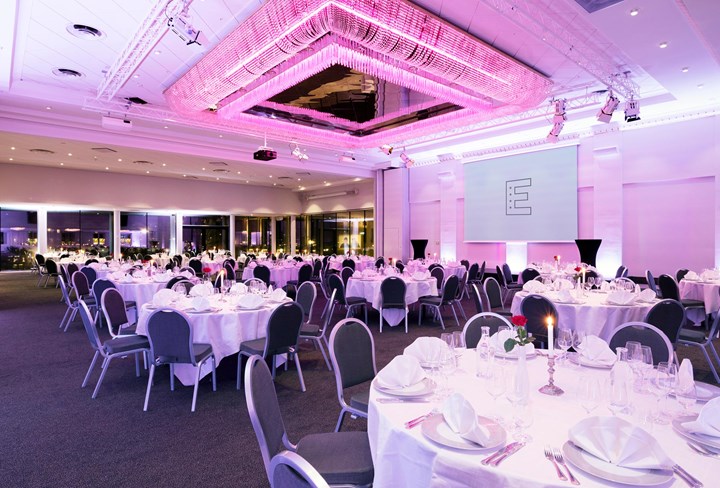 Event with round tables and pink lighting