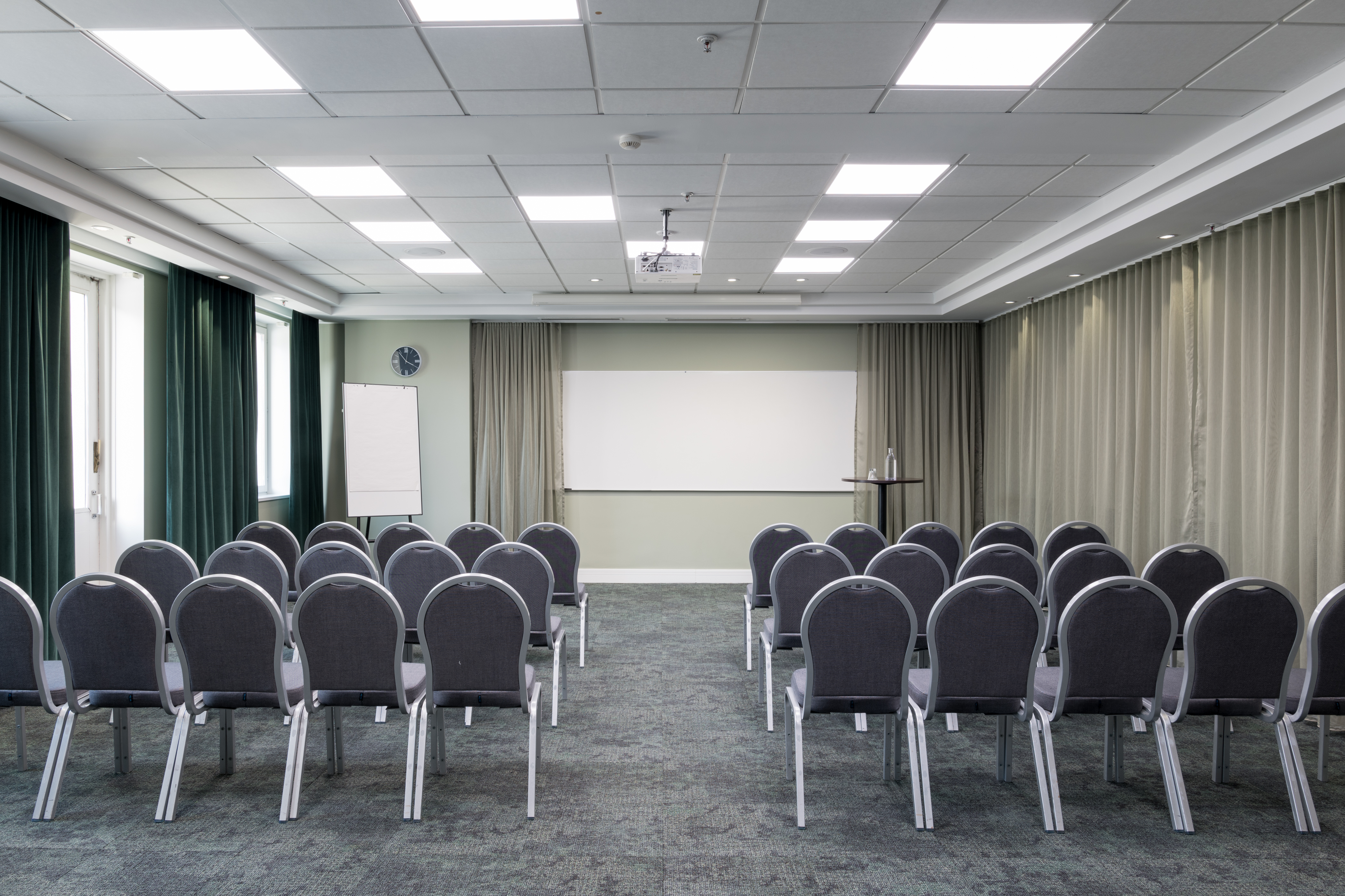 Nice conference room with chairs in rows, curtains, and a whiteboard.