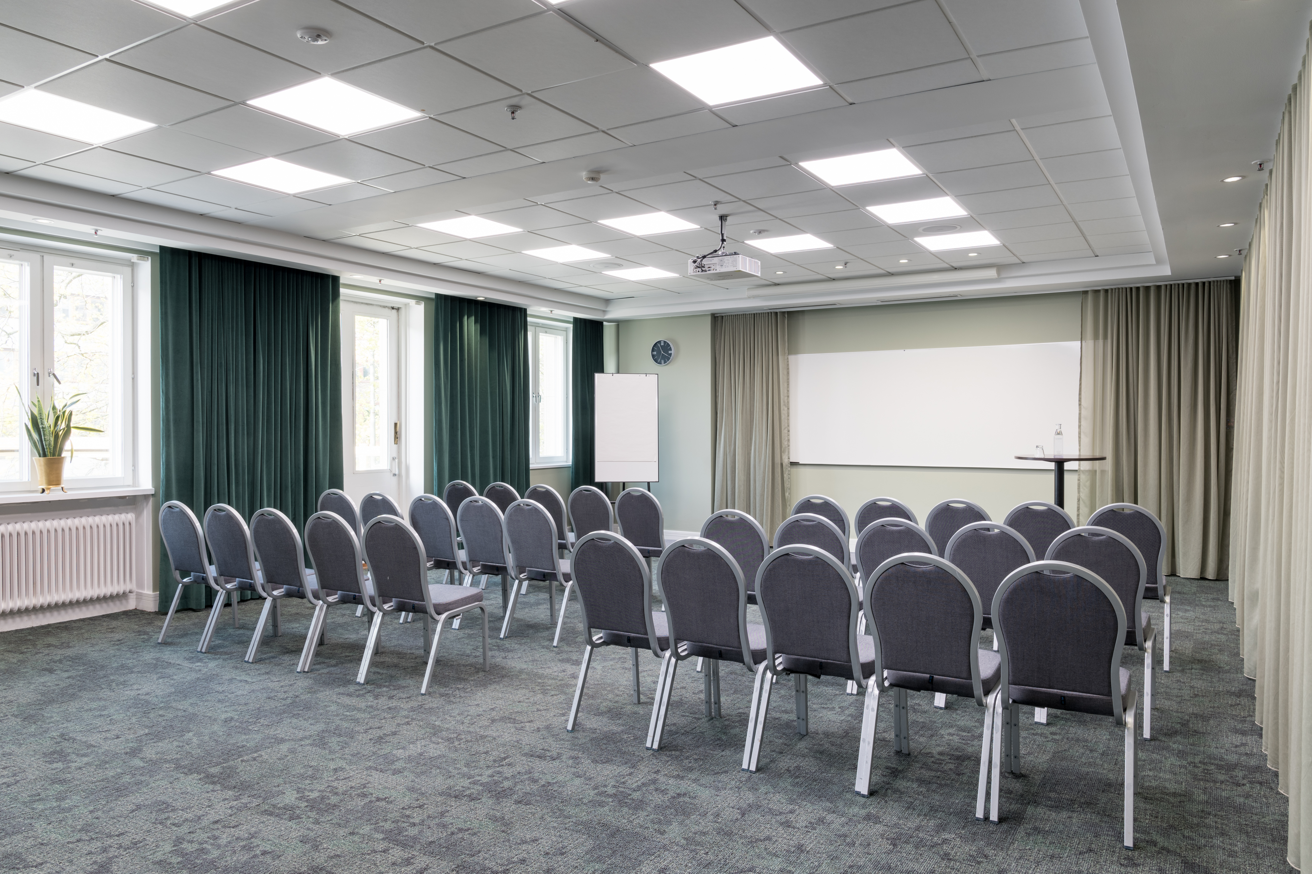 Bright conference room with chairs in rows, windows, and a whiteboard.
