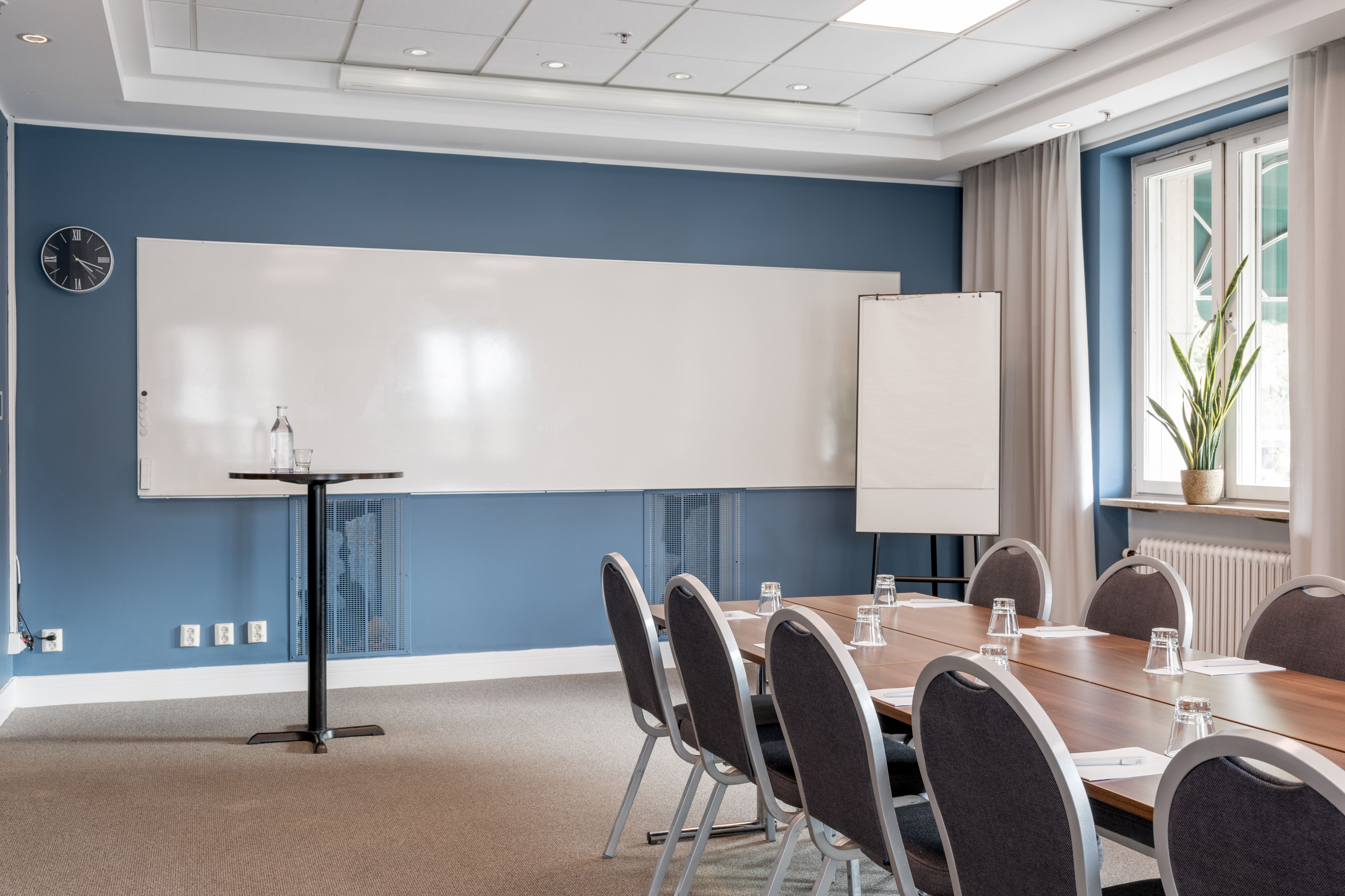 Bright conference room with a large table, chairs, whiteboard, and windows.