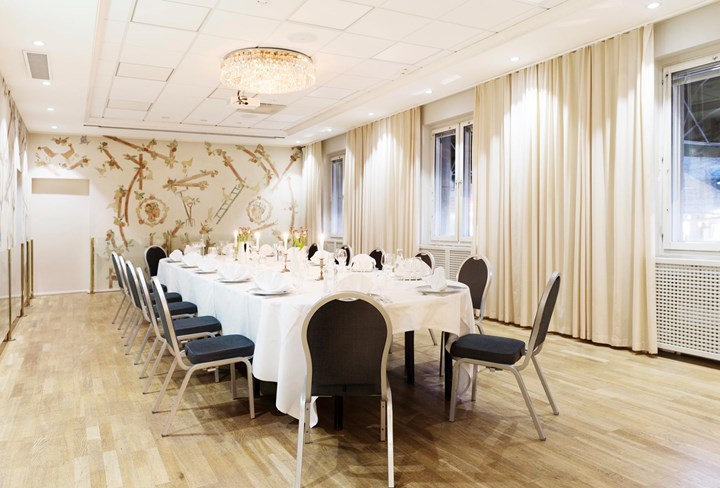 Long set table in hall with white curtains and crystal chandeliers