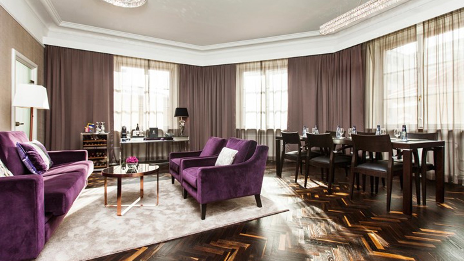 Room with purple sofa and armchairs, as well as a desk and conference table