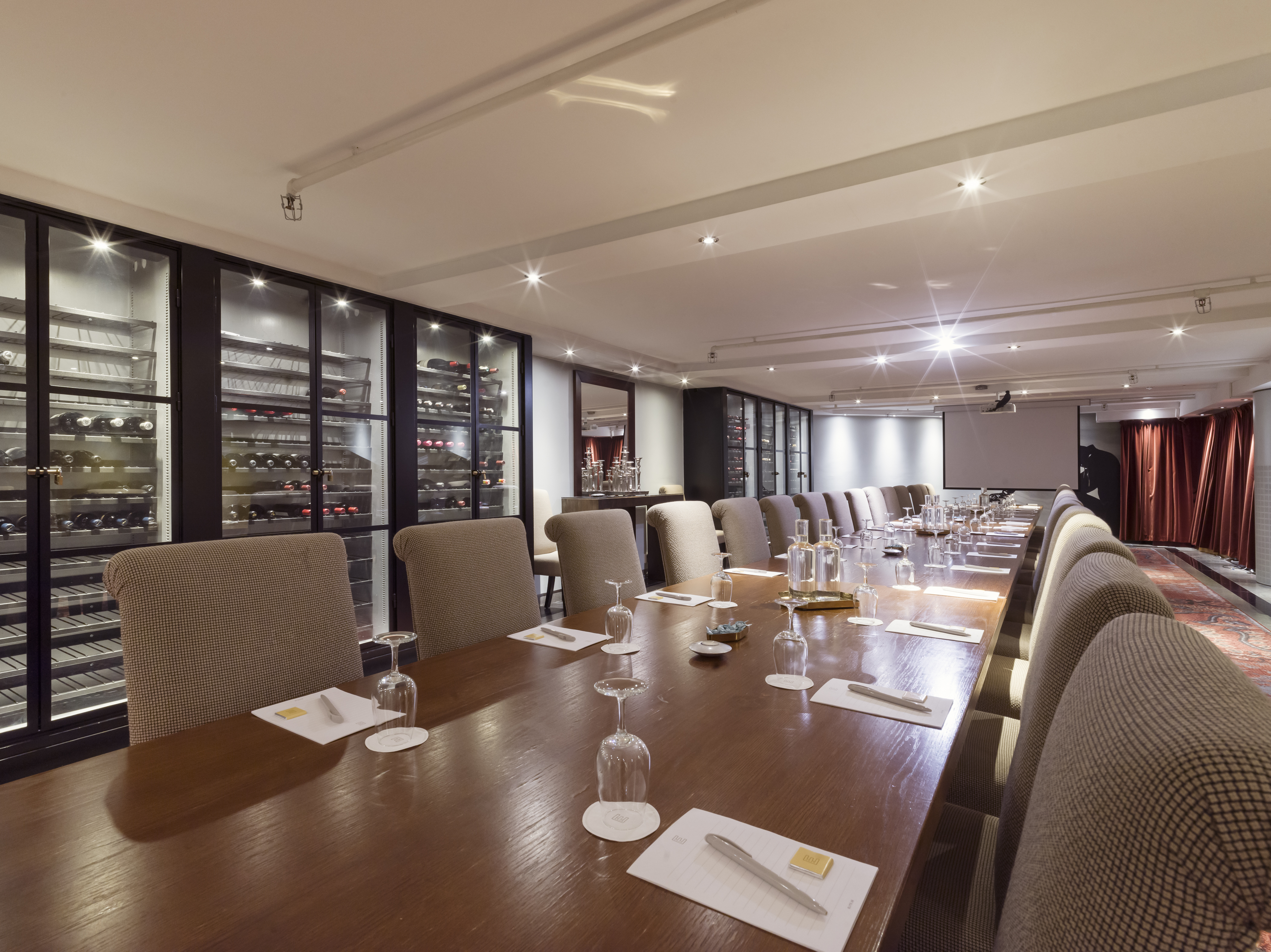 Vinkällare med vinkylar längst väggarna och stort konferensbord