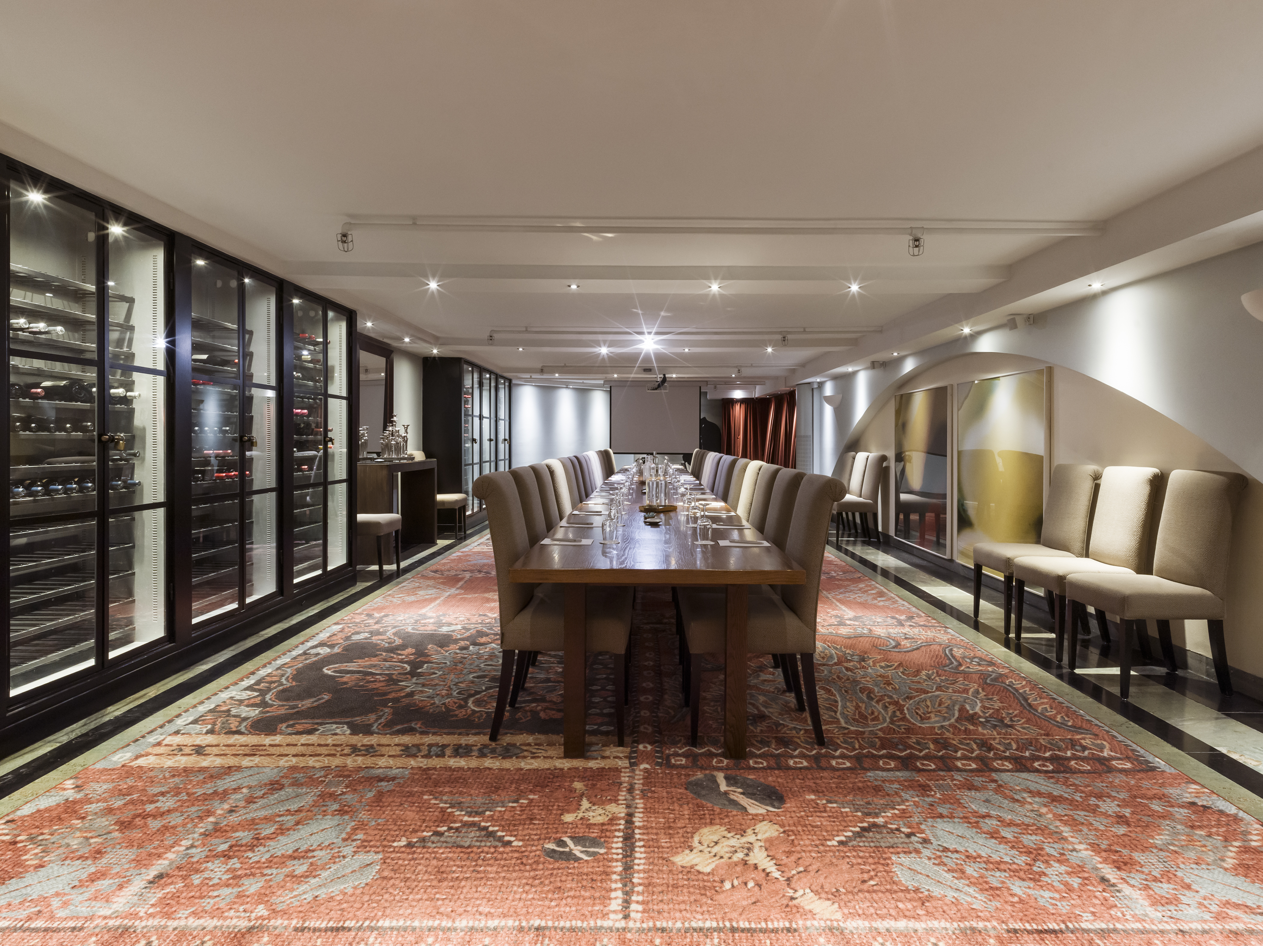 Vinkällare med vinkylar längst väggarna och stort konferensbord