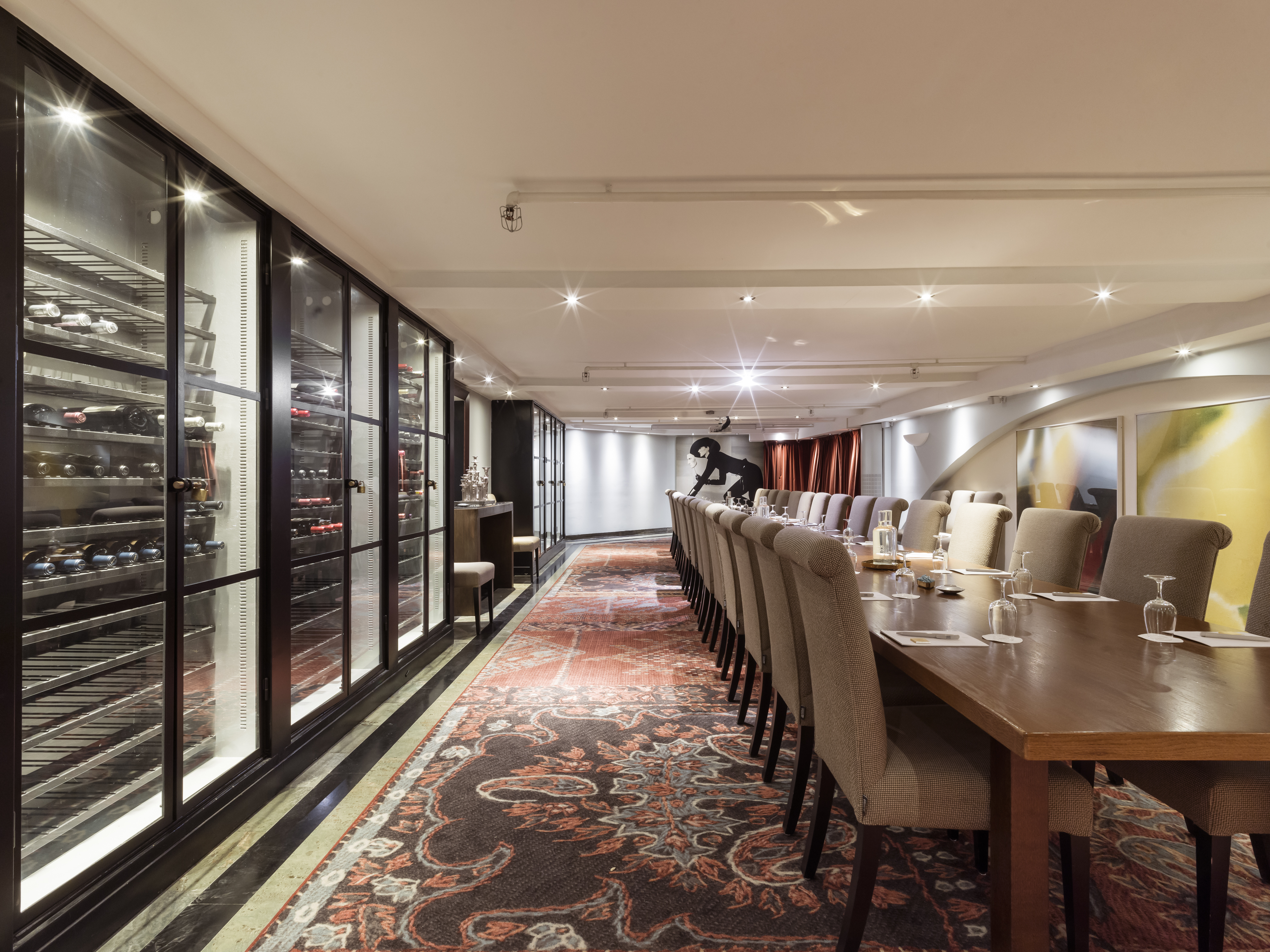 Vinkällare med vinkylar längst väggarna och stort konferensbord