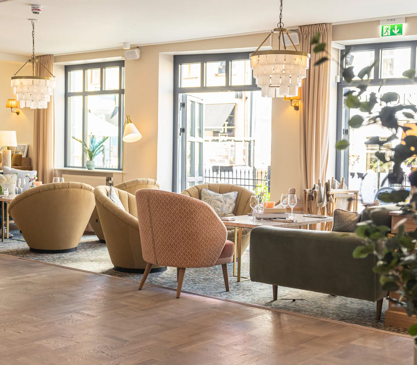 Elegant lobby with nice light, modern furniture, wooden floor and hanging chandeliers.