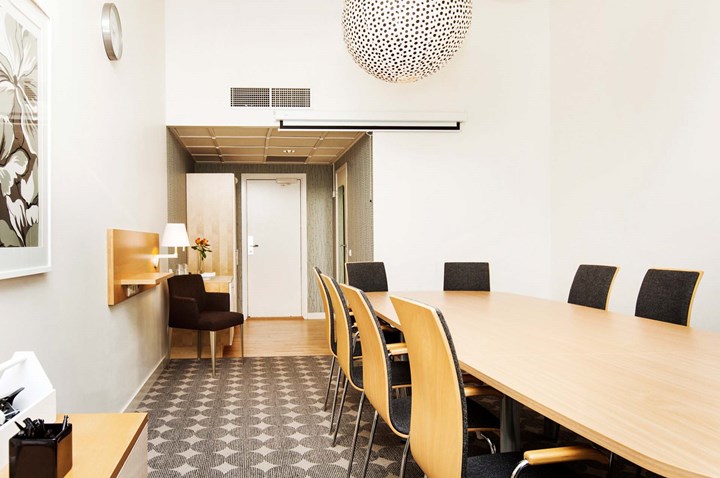 Board room with wooden table, gray patterned carpet and white walls